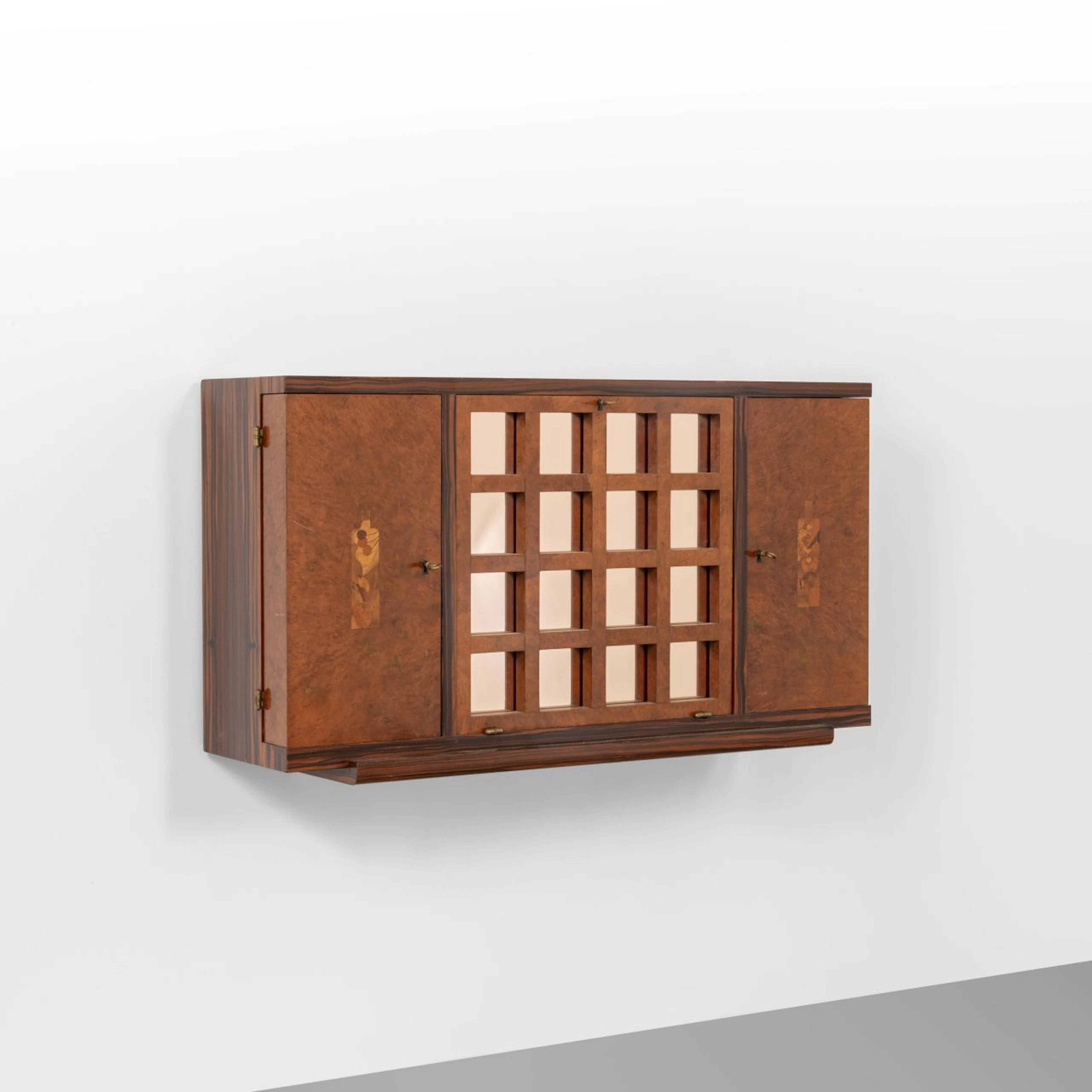 UN MOBILE BAR PENSILE, anni '40. Legno di zebrano, ante in radica