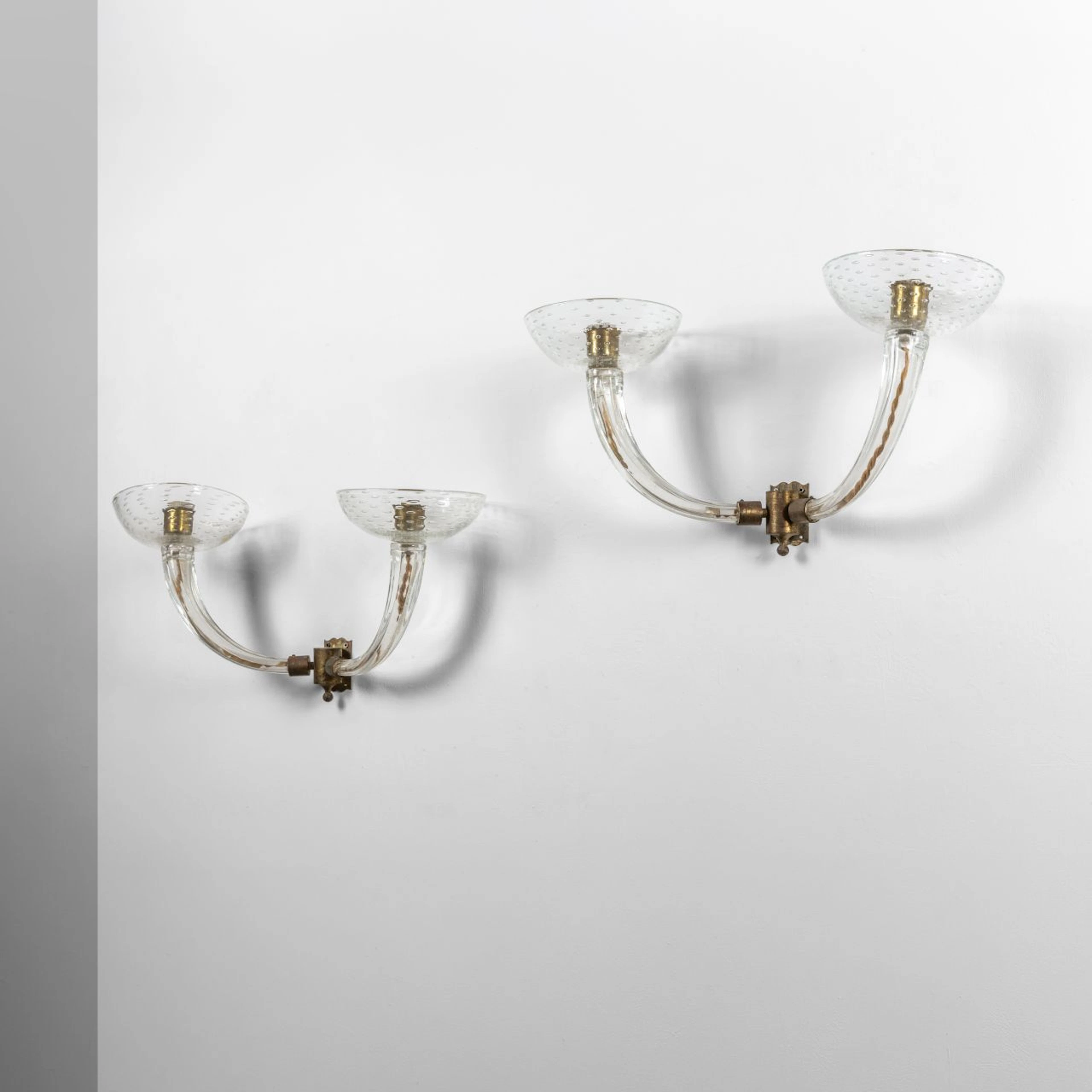 SEGUSO, anni 40. Due lampade da parete. Bracci in vetro scanalato