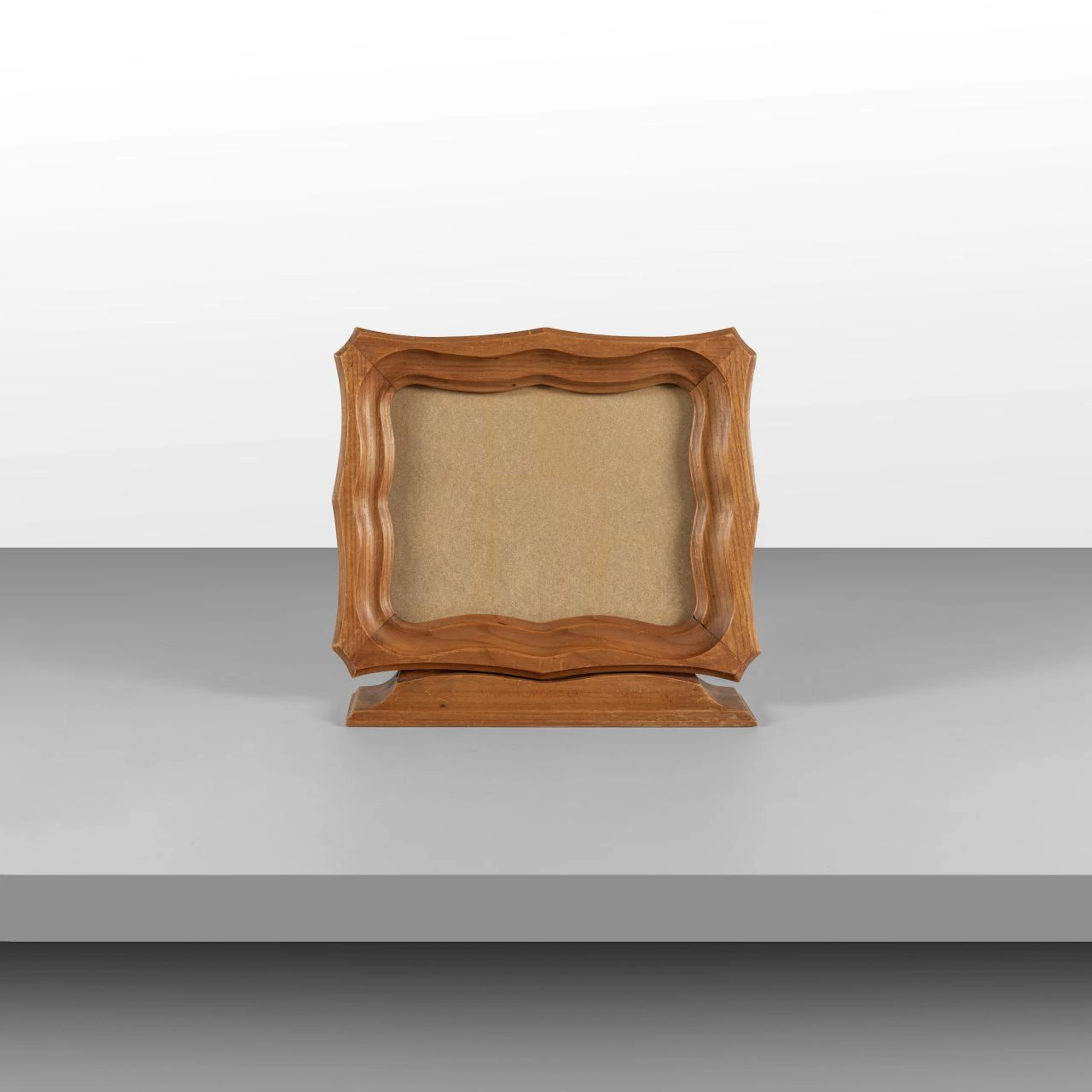 UN PORTARITRATTI, anni '50. Legno intagliato, cristallo. Posizionabile