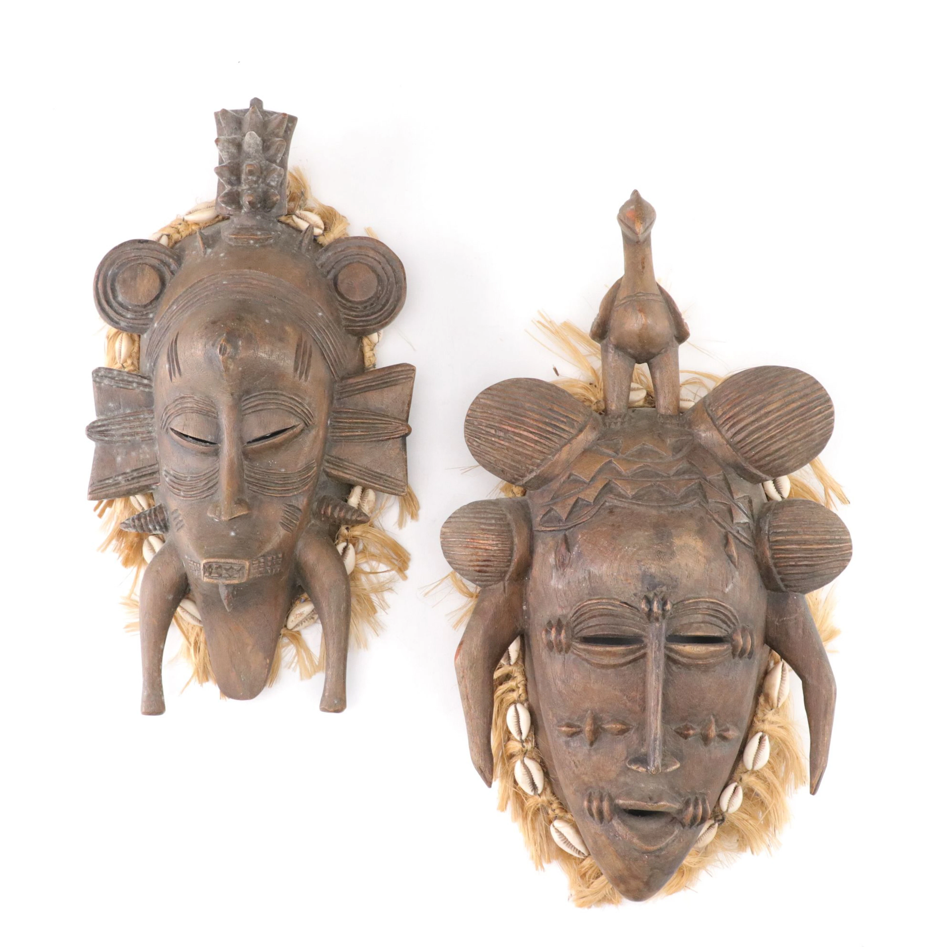 Two Senufo Kpelie Style Carved Wood Masks with Raffia and Shelf Fringe