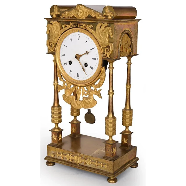 EMPIRE CLOCK in gilded bronze with four small columns supporting a