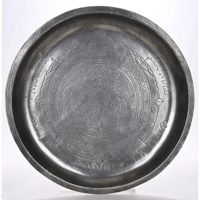 A pewter PLAT D’ARRAS depicting an engraved crucifixion scene. It