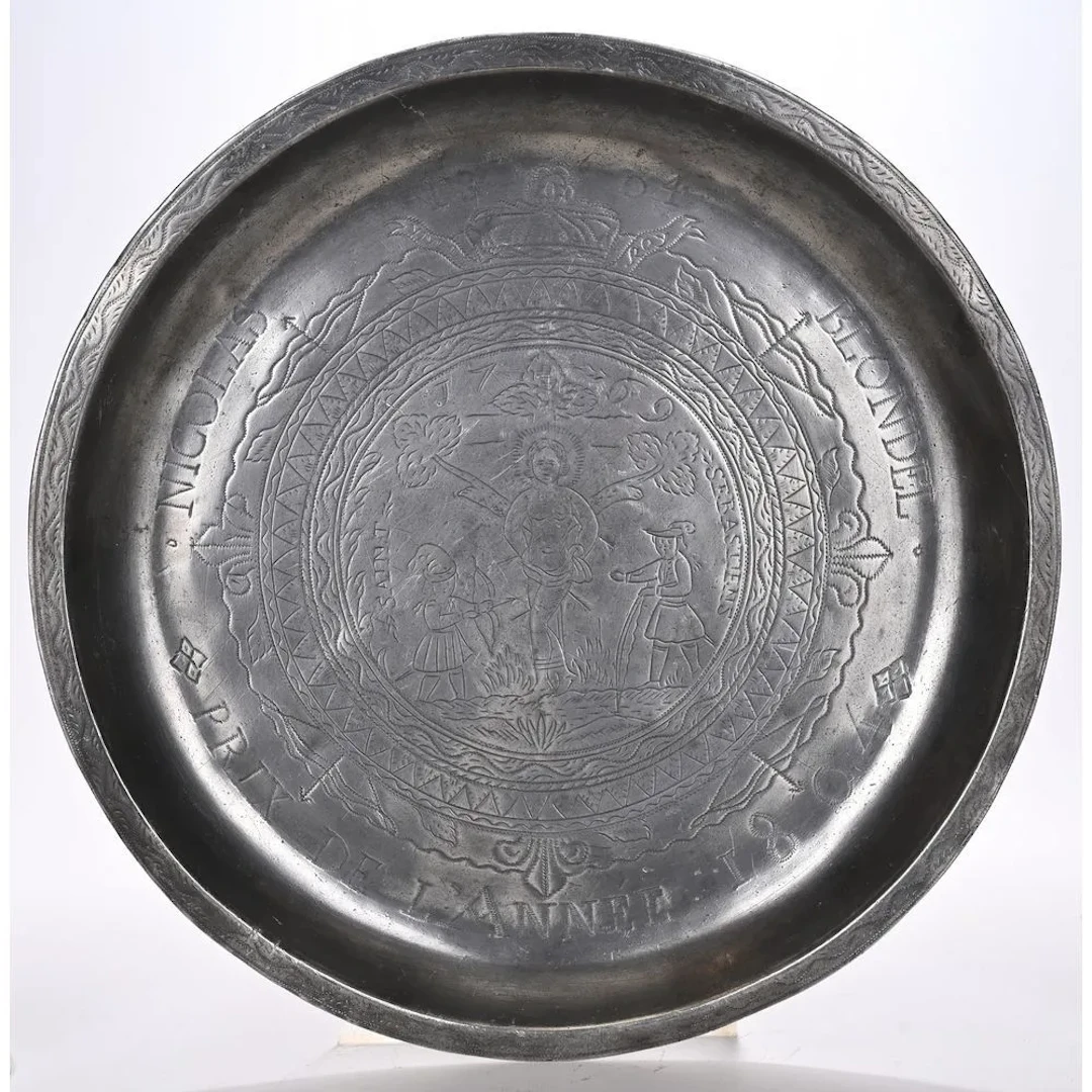 A pewter PLAT D’ARRAS depicting an engraved crucifixion scene. It