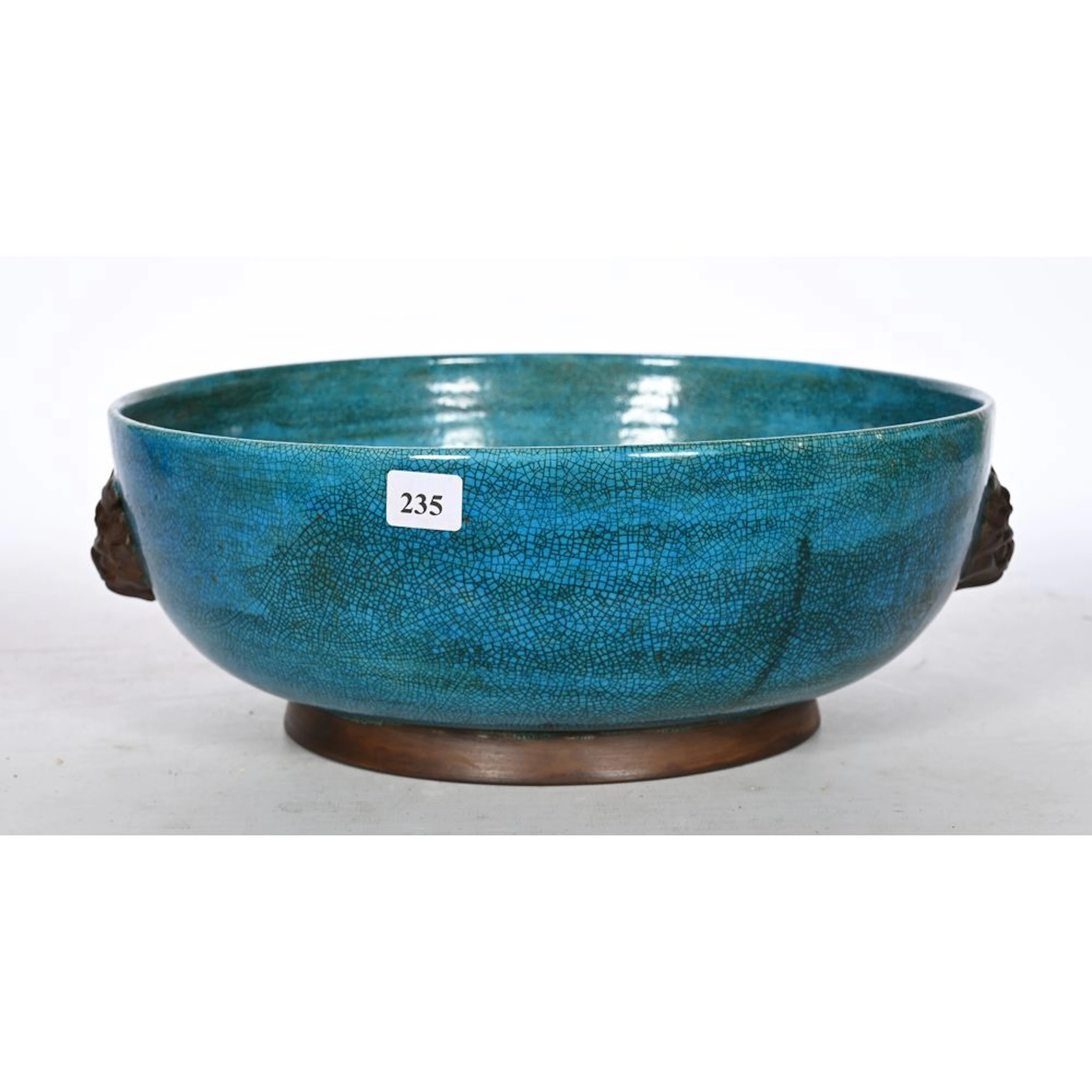 Ceramic bowl with a crackled finish on a bluish background. Handles