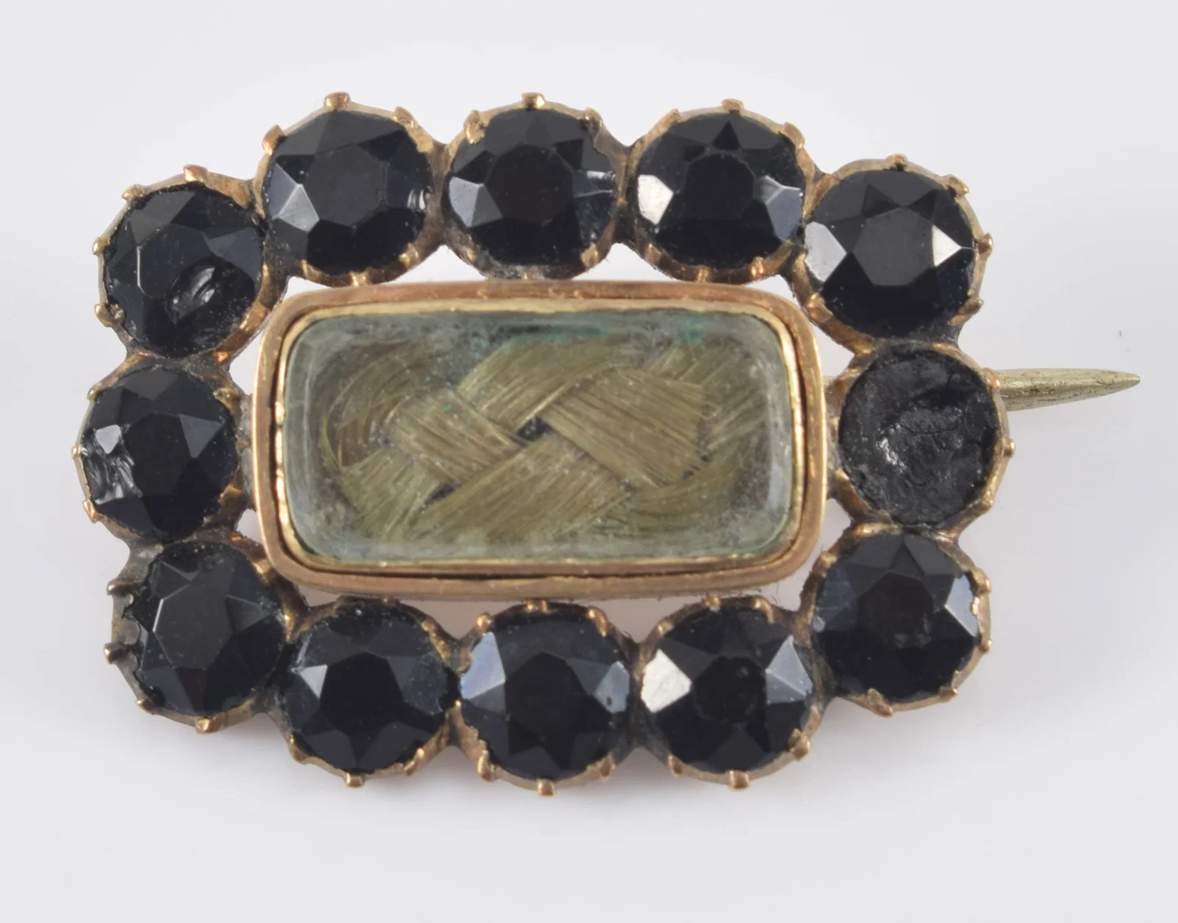 1828 mourning pin with hair braid surrounded by faceted jet stones.
