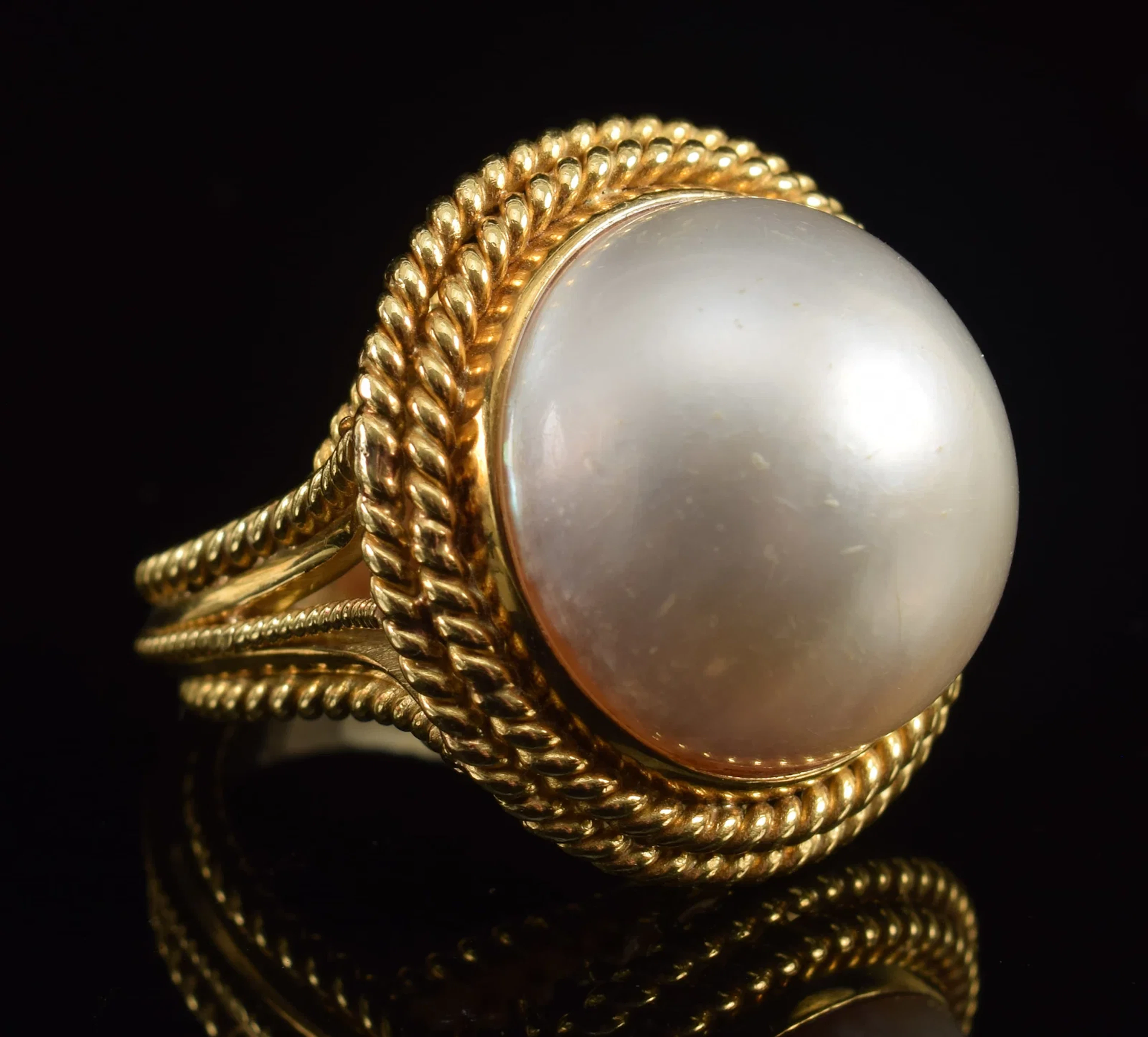 18K gold mabe pearl ring. Reticulated setting with braided band decoration.