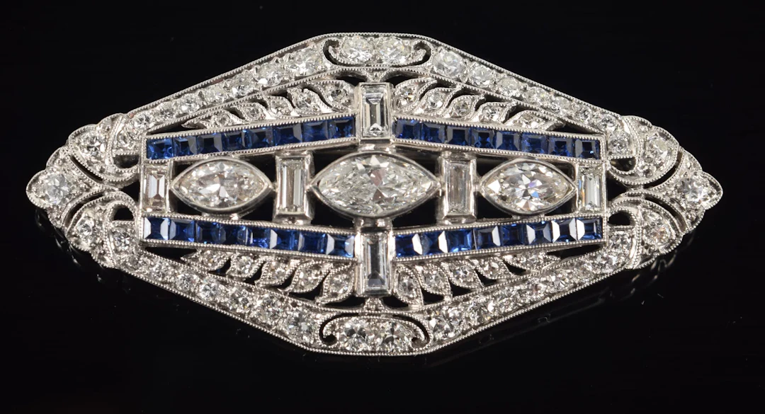 Art Deco 18K white gold diamond and sapphire brooch. Center set with