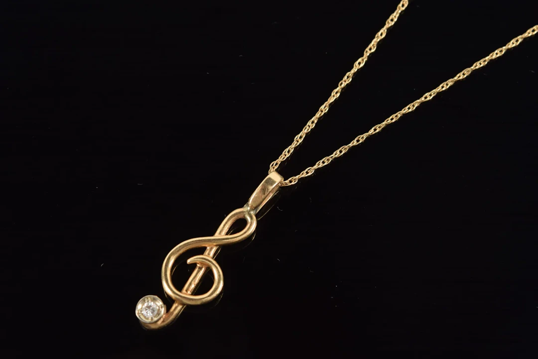 14K gold diamond mounted musical note pendant necklace. Diamond approx.