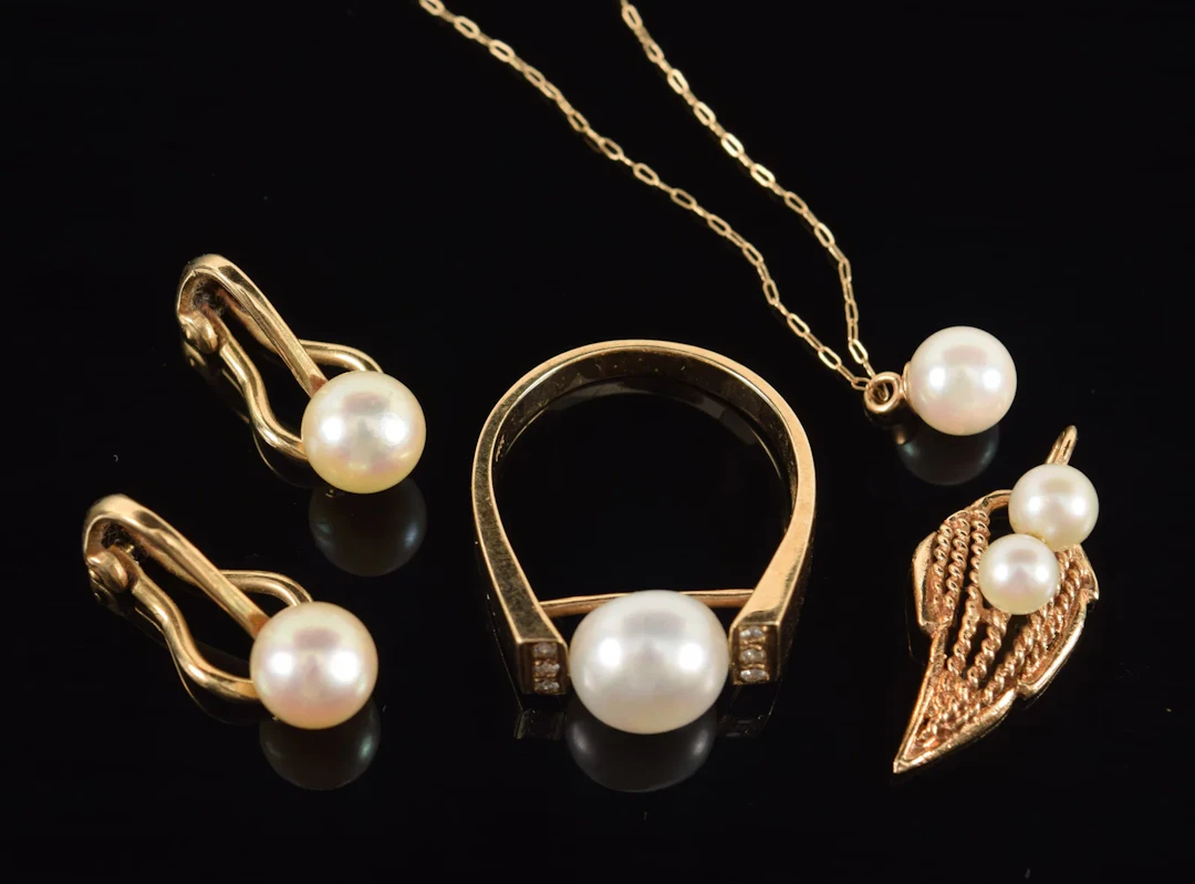 Lot of gold pearl jewelry. To include: pair of clip earrings, ring