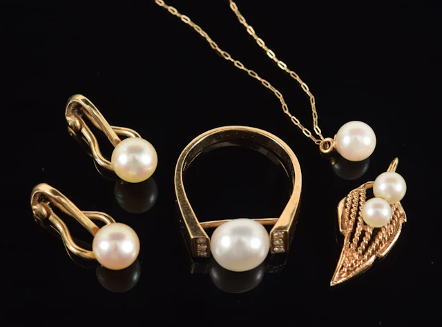 Lot of gold pearl jewelry. To include: pair of clip earrings, ring