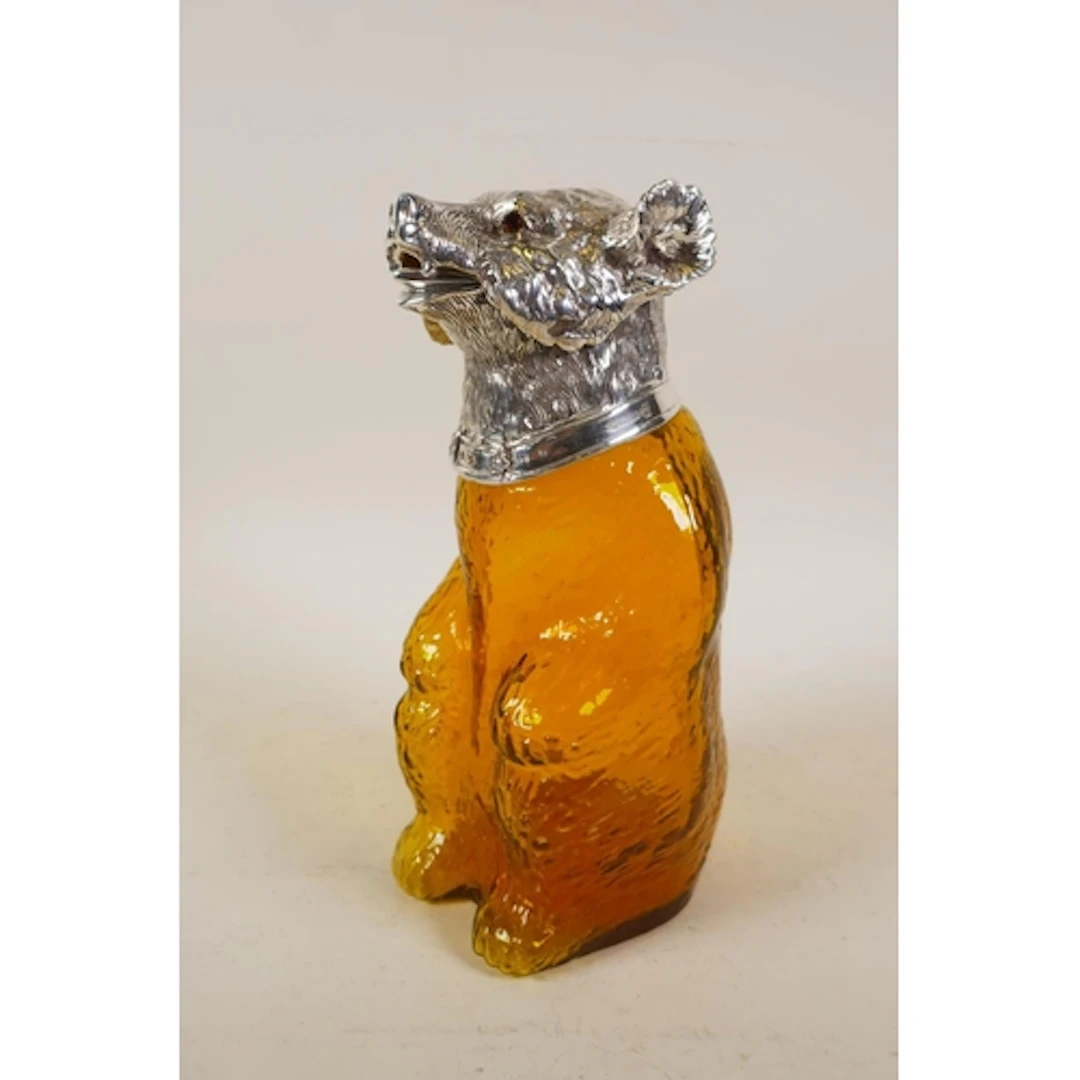 A silver plated and yellow glass claret jug in the form of a...