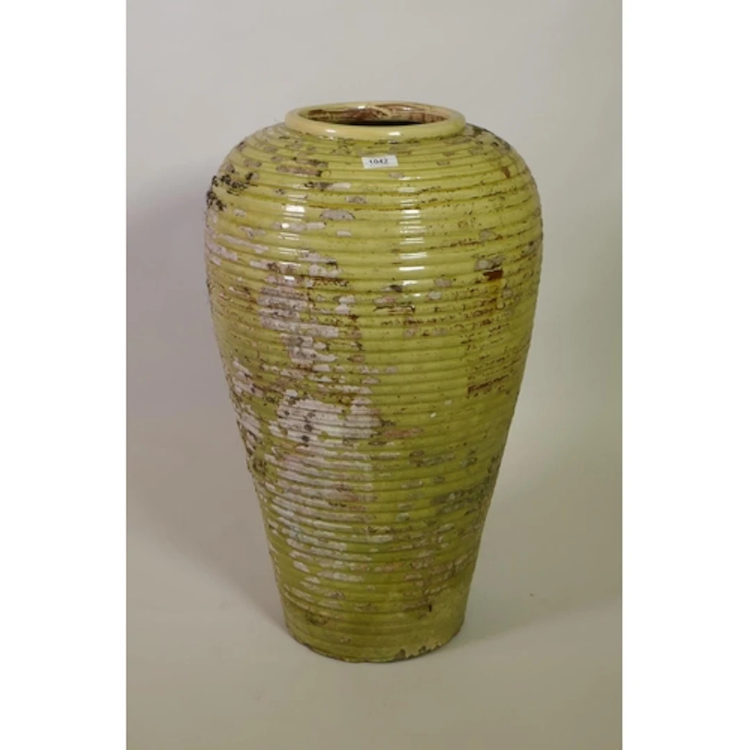 A large ribbed terracotta olive jar with the remnants of gre...