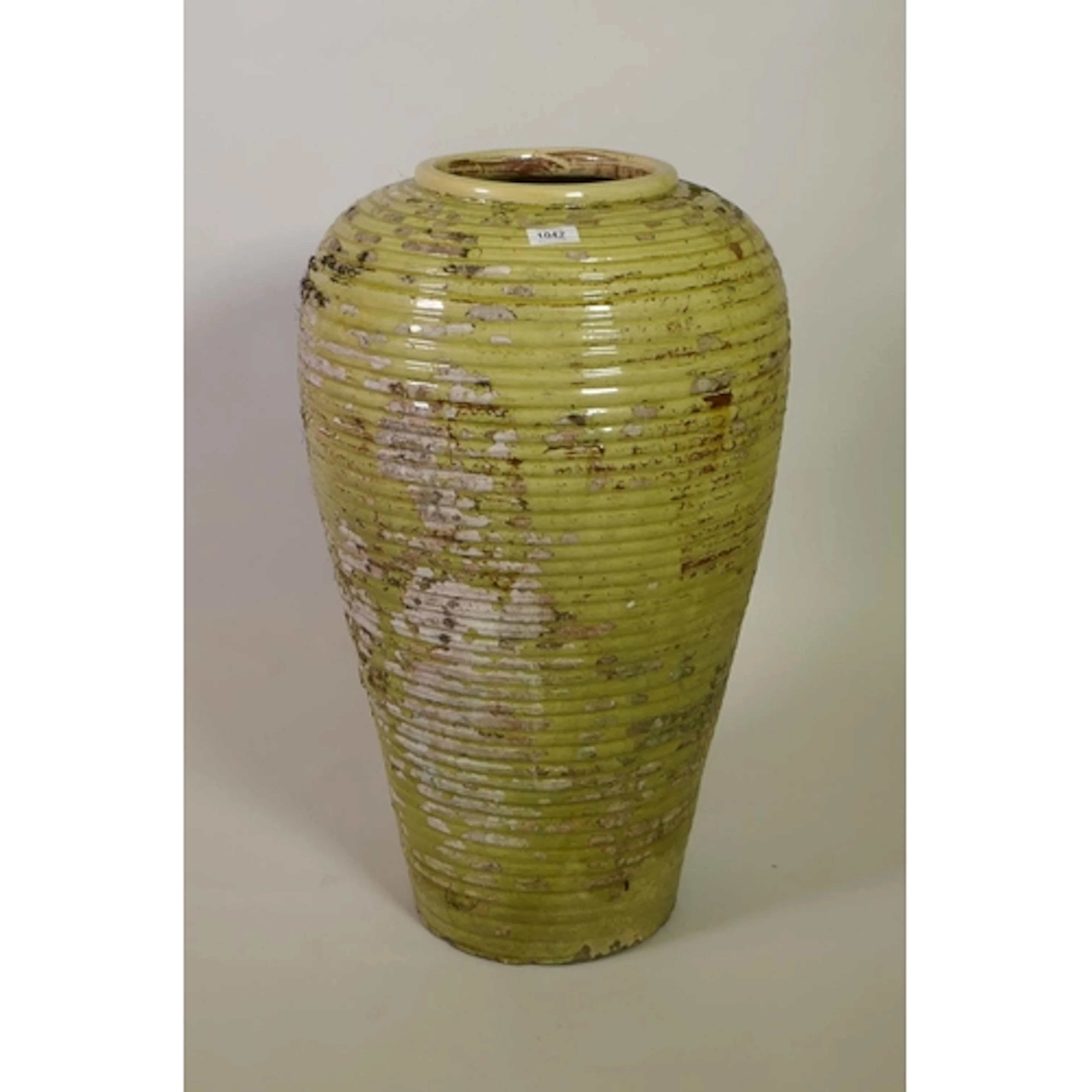 A large ribbed terracotta olive jar with the remnants of gre...