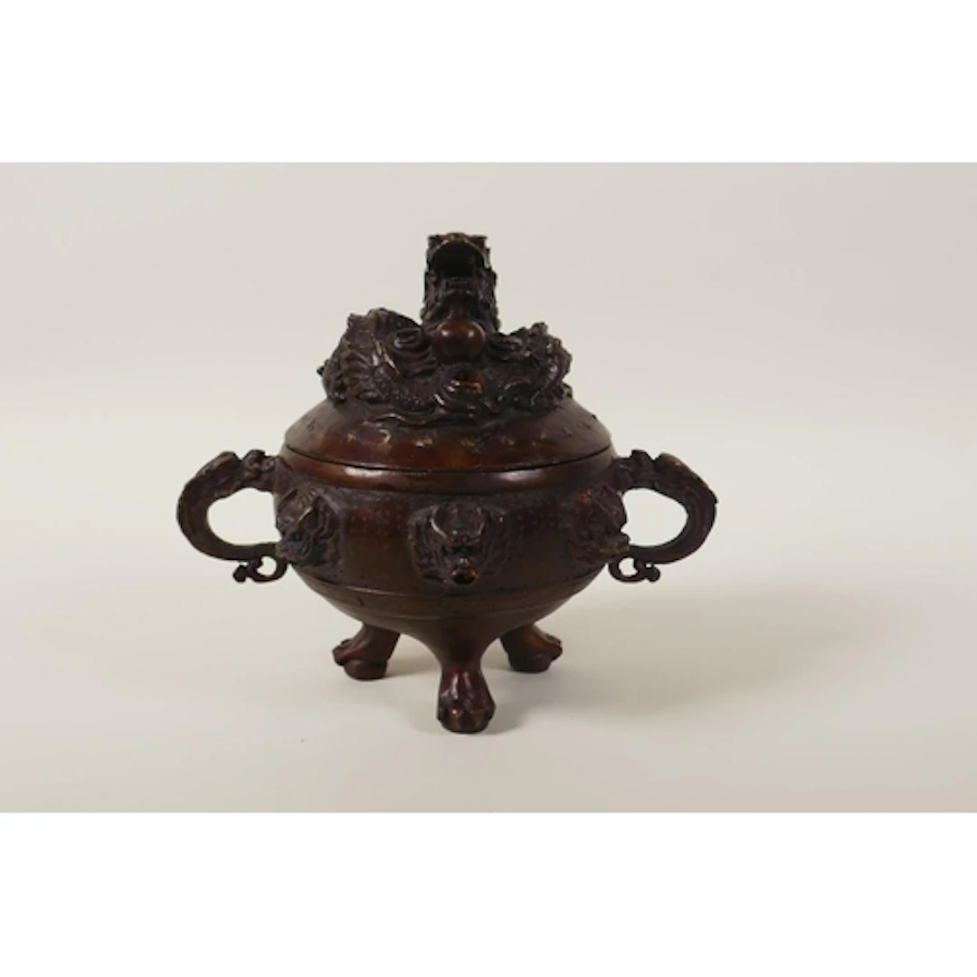 A Chinese bronze two handled censer and cover on tripod supp...