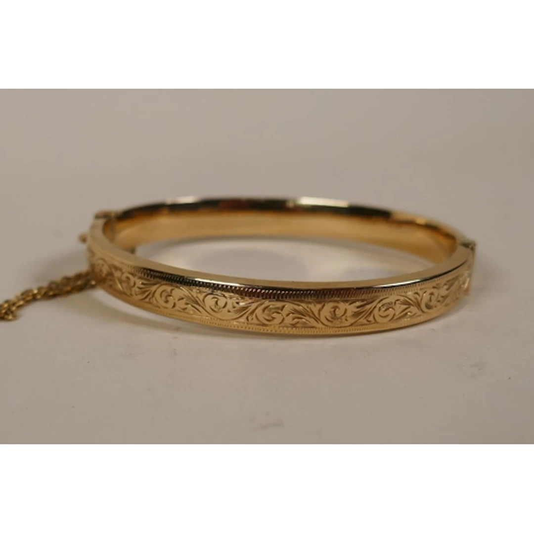 9ct gold bangle with engraved decoration, 6.2cm internal dia...