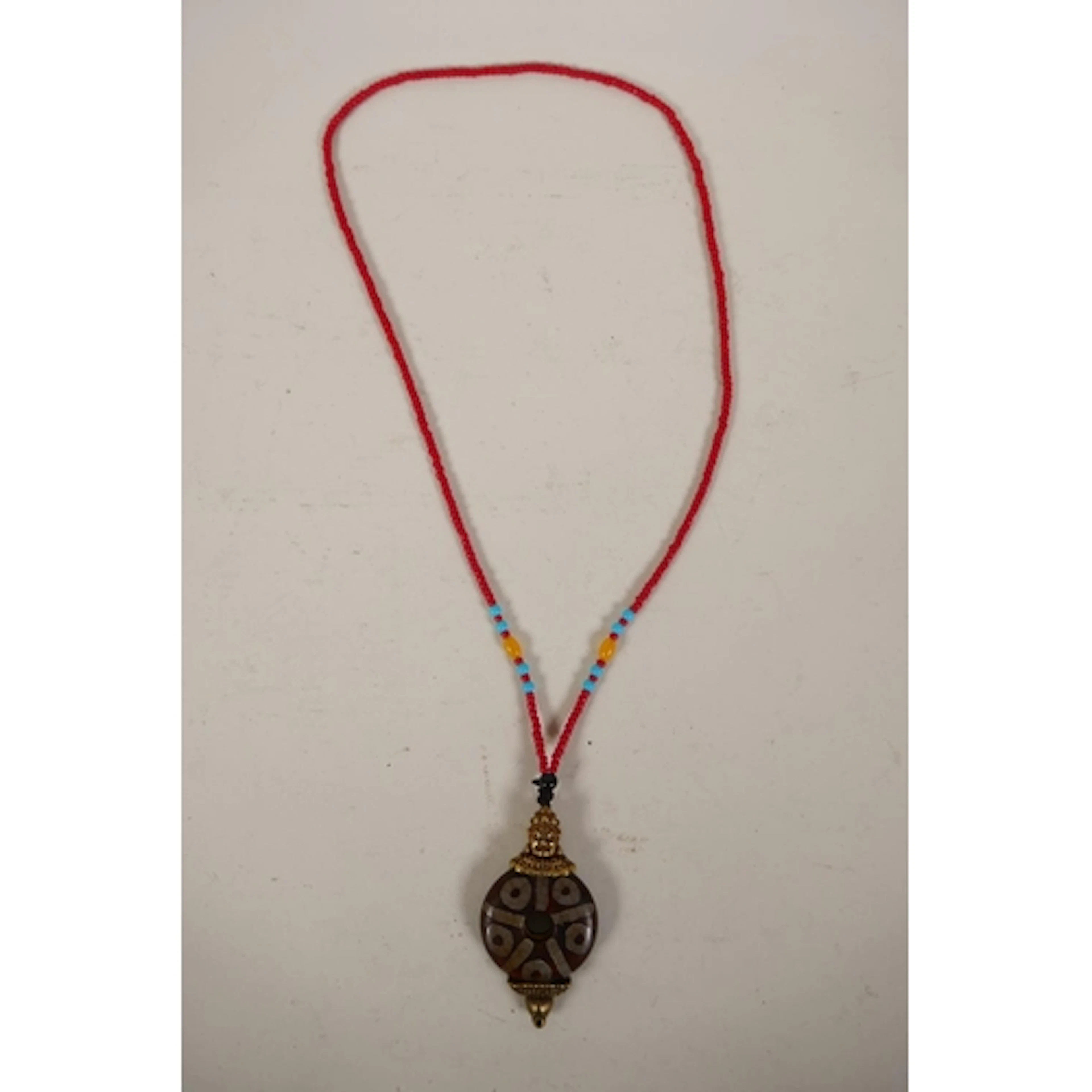 A Tibetan dzi bead style brass mounted pendant necklace, pen...
