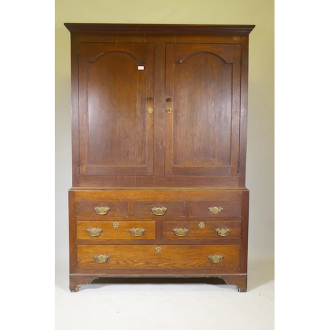 A Georgian oak livery cupboard, the upper section with two a...