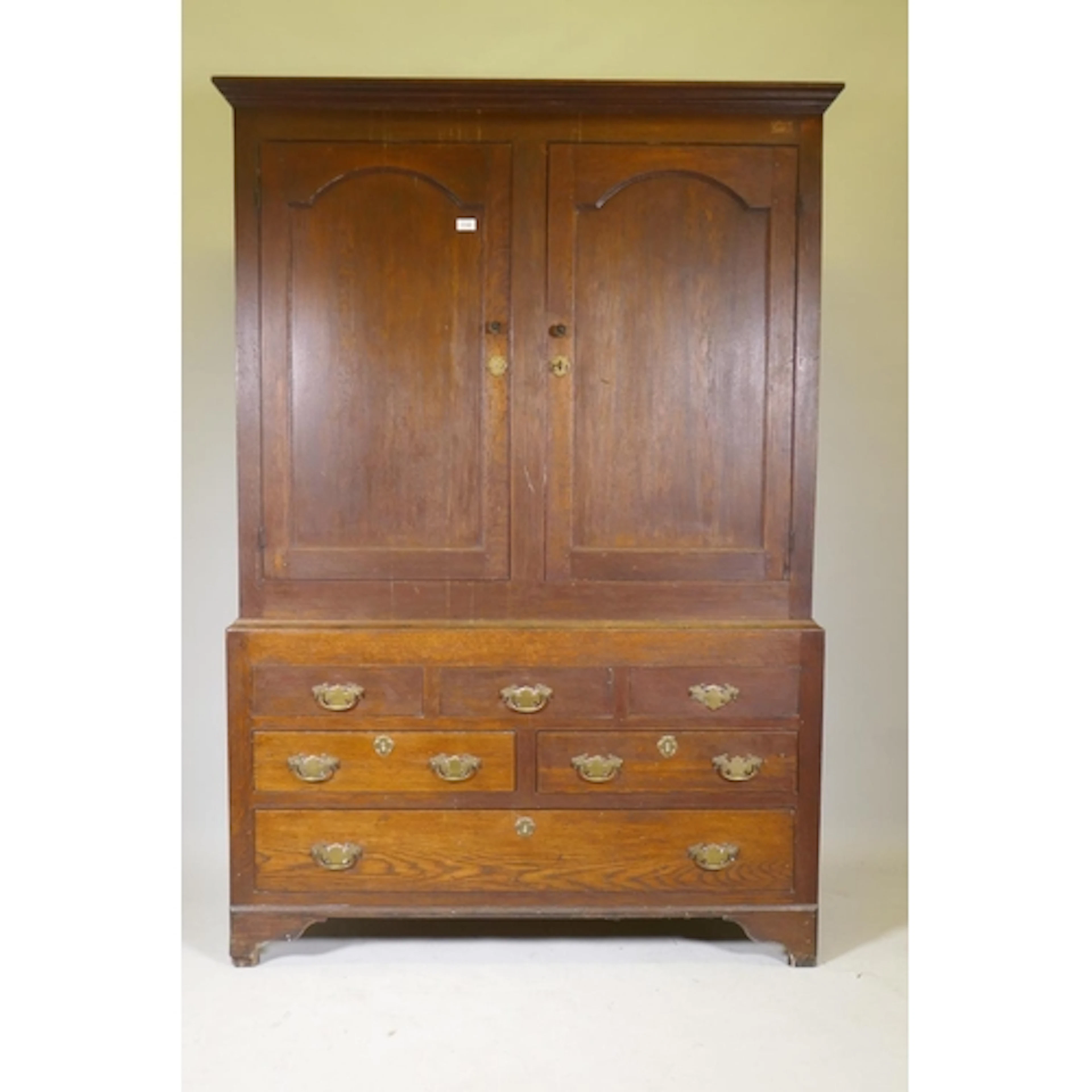 A Georgian oak livery cupboard, the upper section with two a...