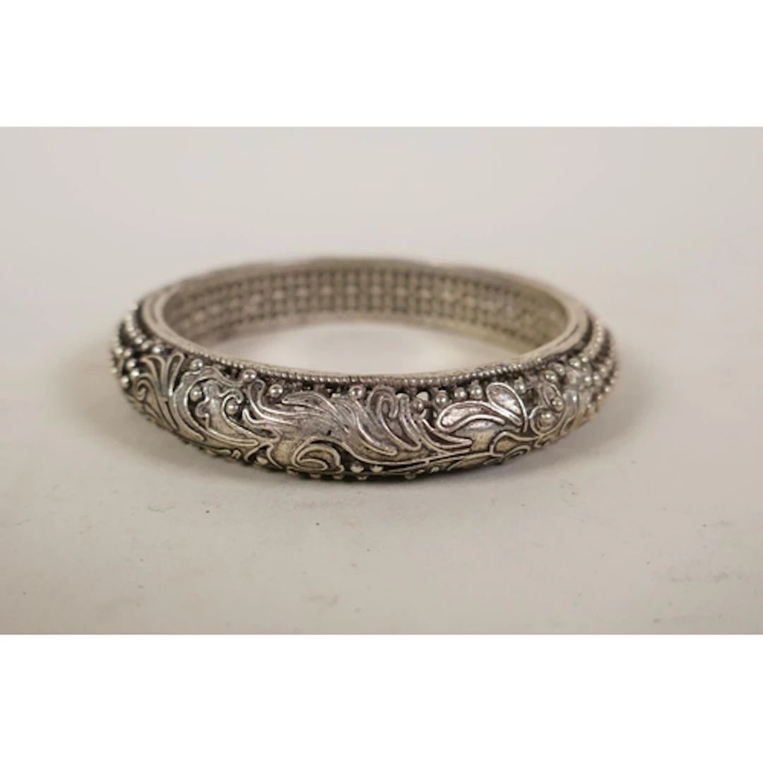 An oriental pierced white metal bangle, 8cm diameter