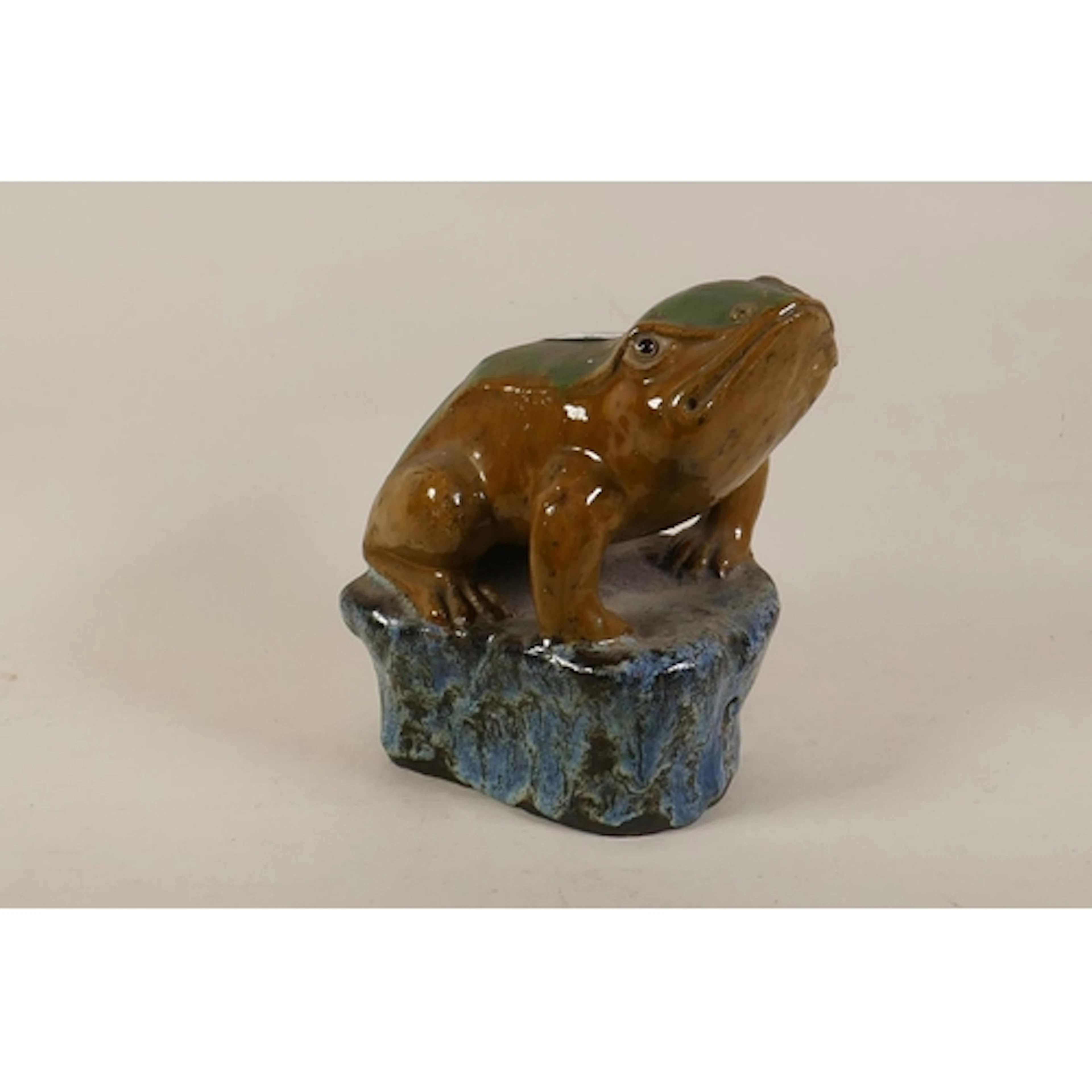 A glazed stoneware figure of a frog seated upon a rock, 24cm...