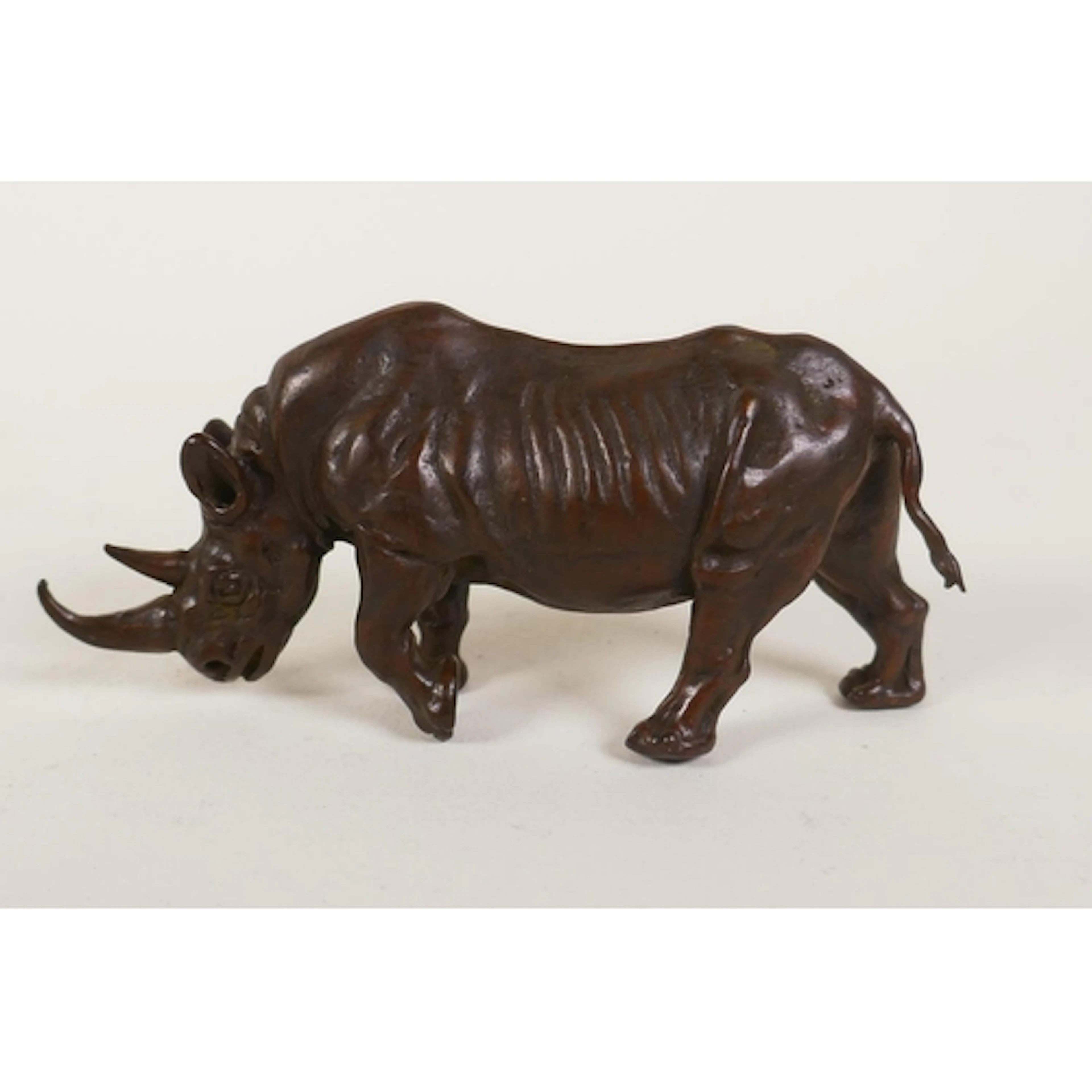 A miniature bronzed metal rhinoceros, 9cm long