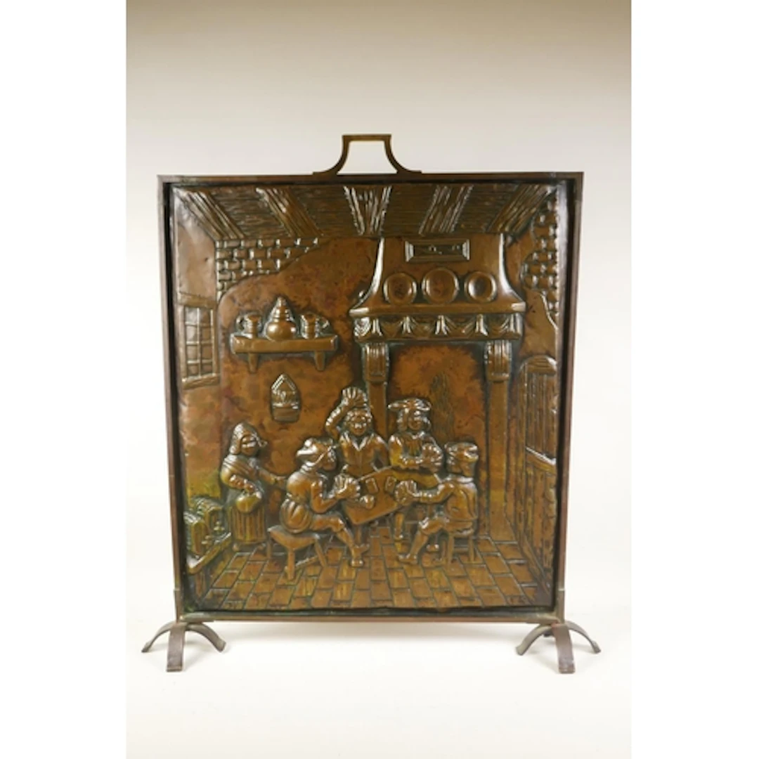 A copper and brass fire guard featuring a tavern scene with ...