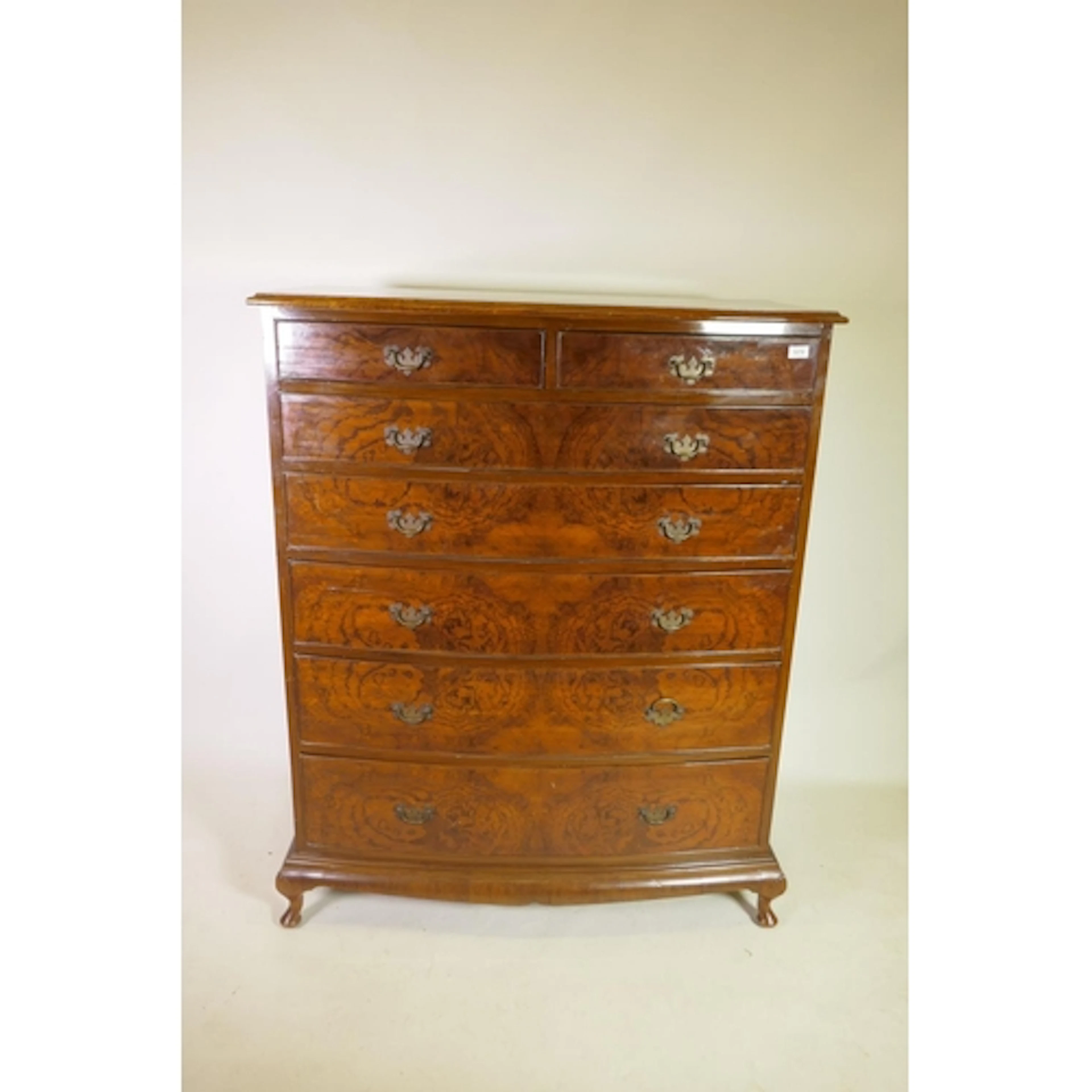 A figured and grained walnut bow front chest of two over fiv...