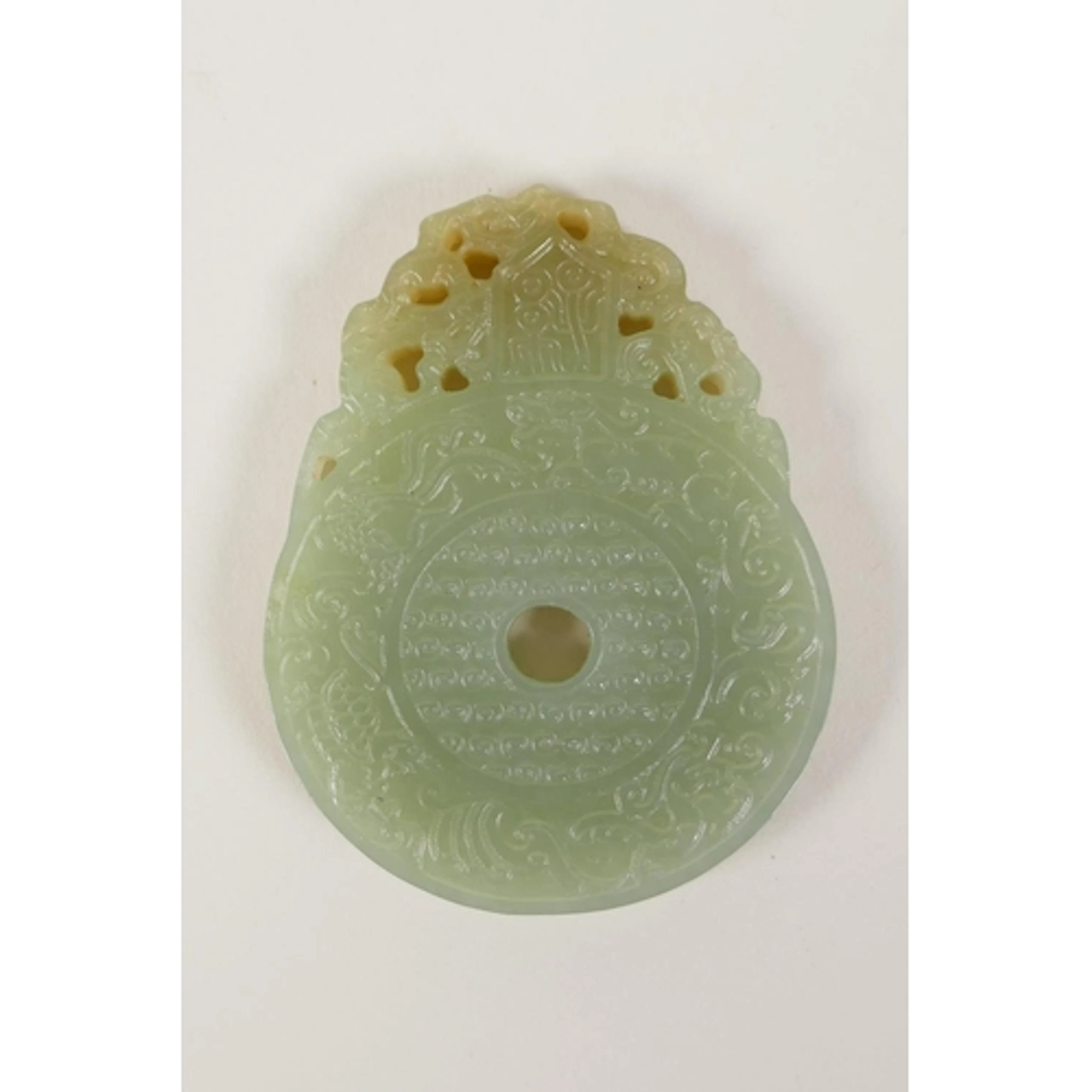 A Chinese carved celadon jade pi-disc pendant, 7cm