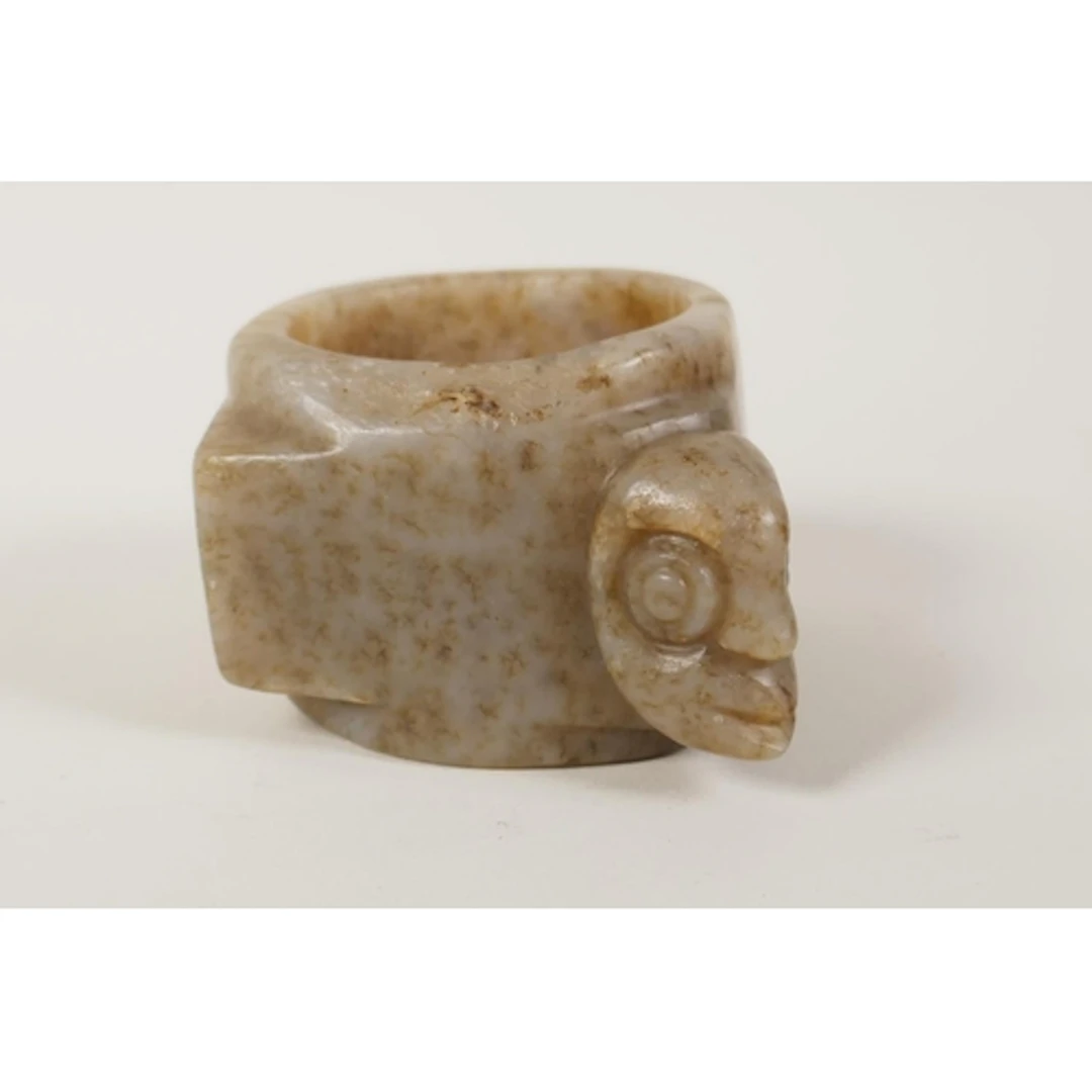 A Chinese nephrite jade bangle with carved mask decoration, ...