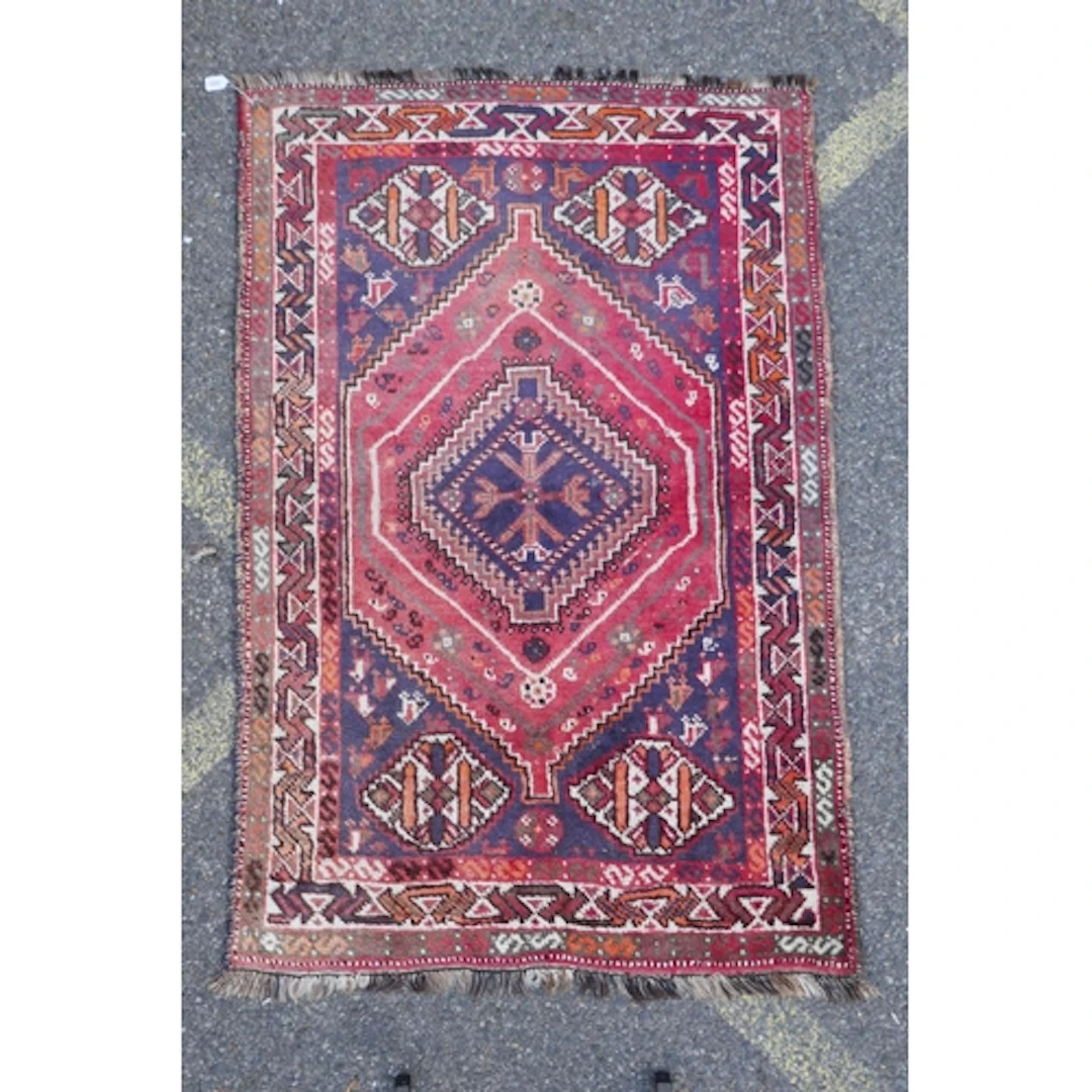A Persian red and blue ground Ghashghai wool rug with a cent...