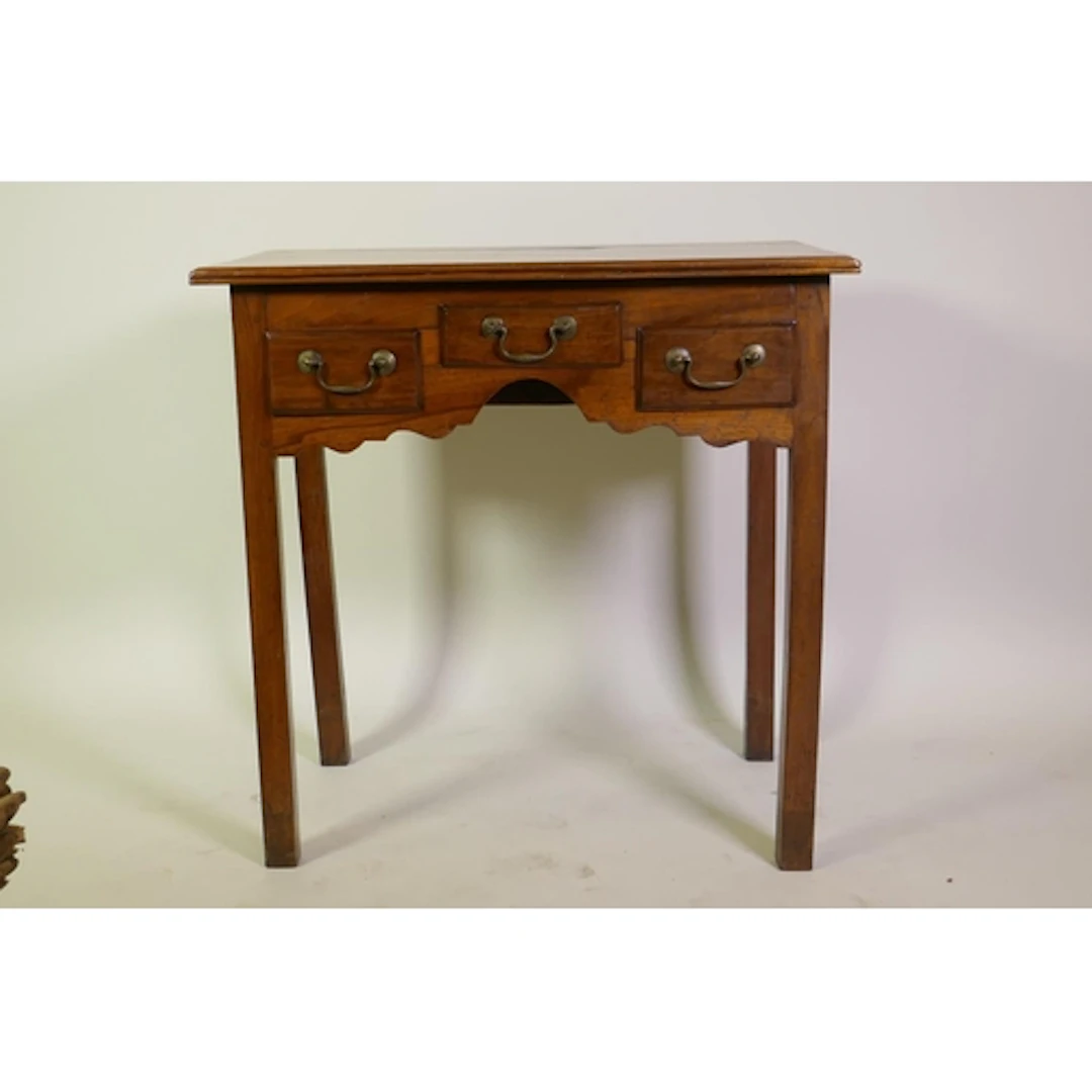 A Georgian walnut lowboy, with reeded edge top over three dr...