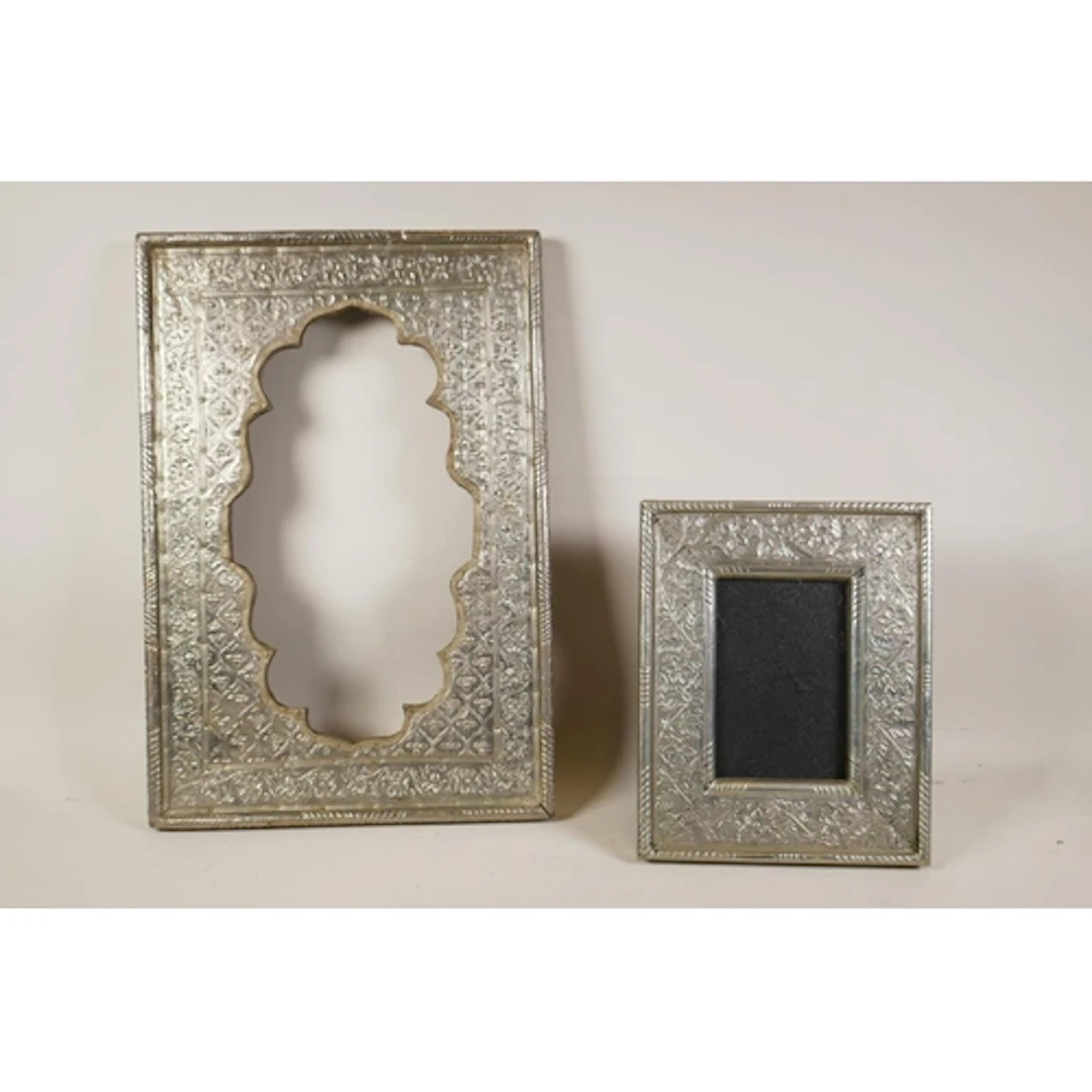 An Indian white metal mirror frame with repousse foliate dec...
