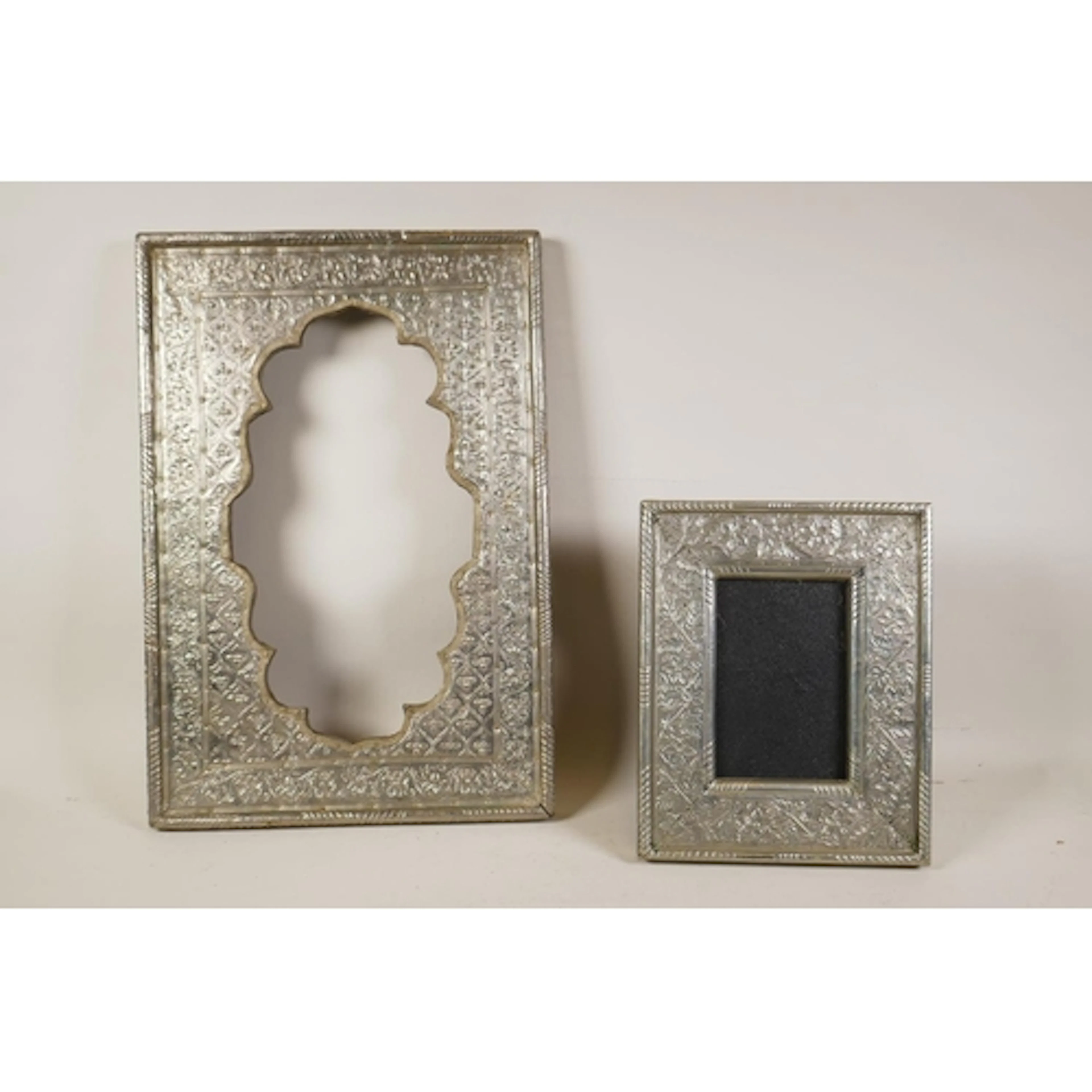 An Indian white metal mirror frame with repousse foliate dec...