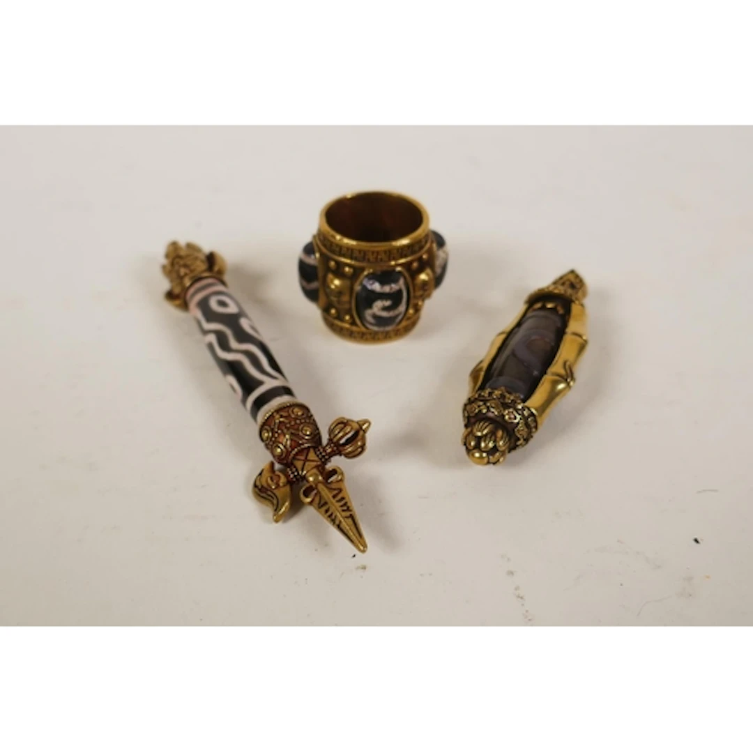 A Tibetan brass mounted dzi bead in the form of a phurba and...
