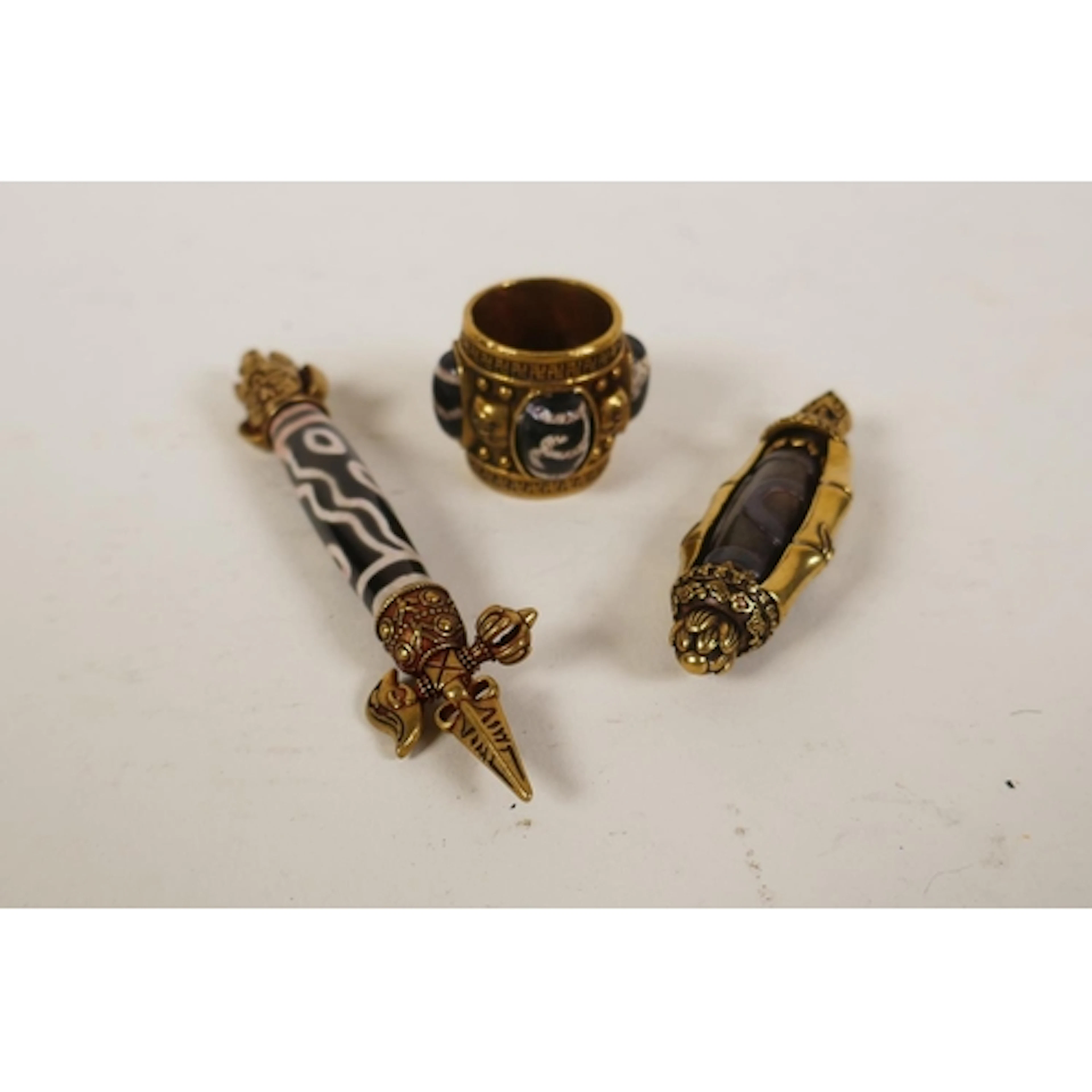 A Tibetan brass mounted dzi bead in the form of a phurba and...