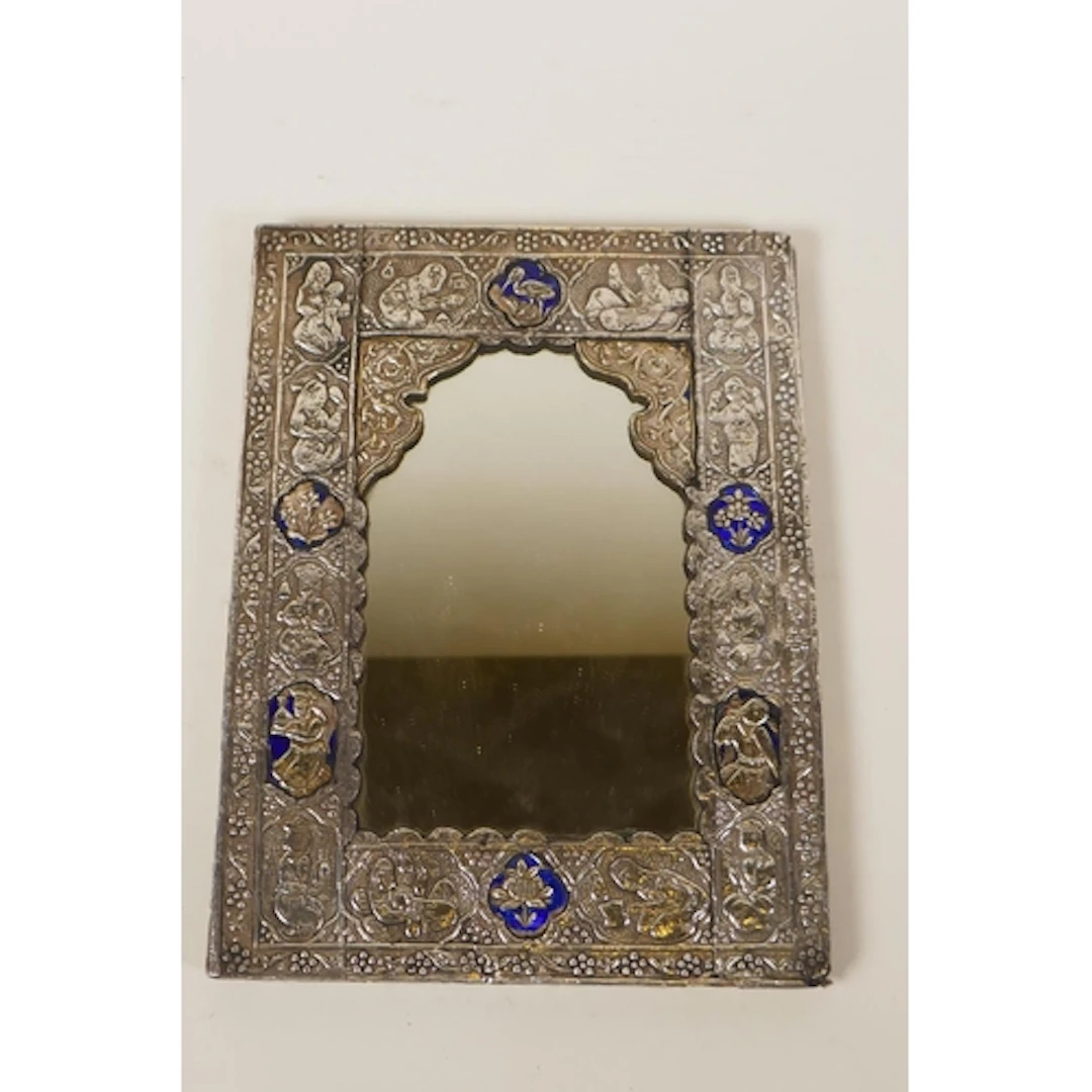 An Indo Persian white metal framed mirror with repousse figu...