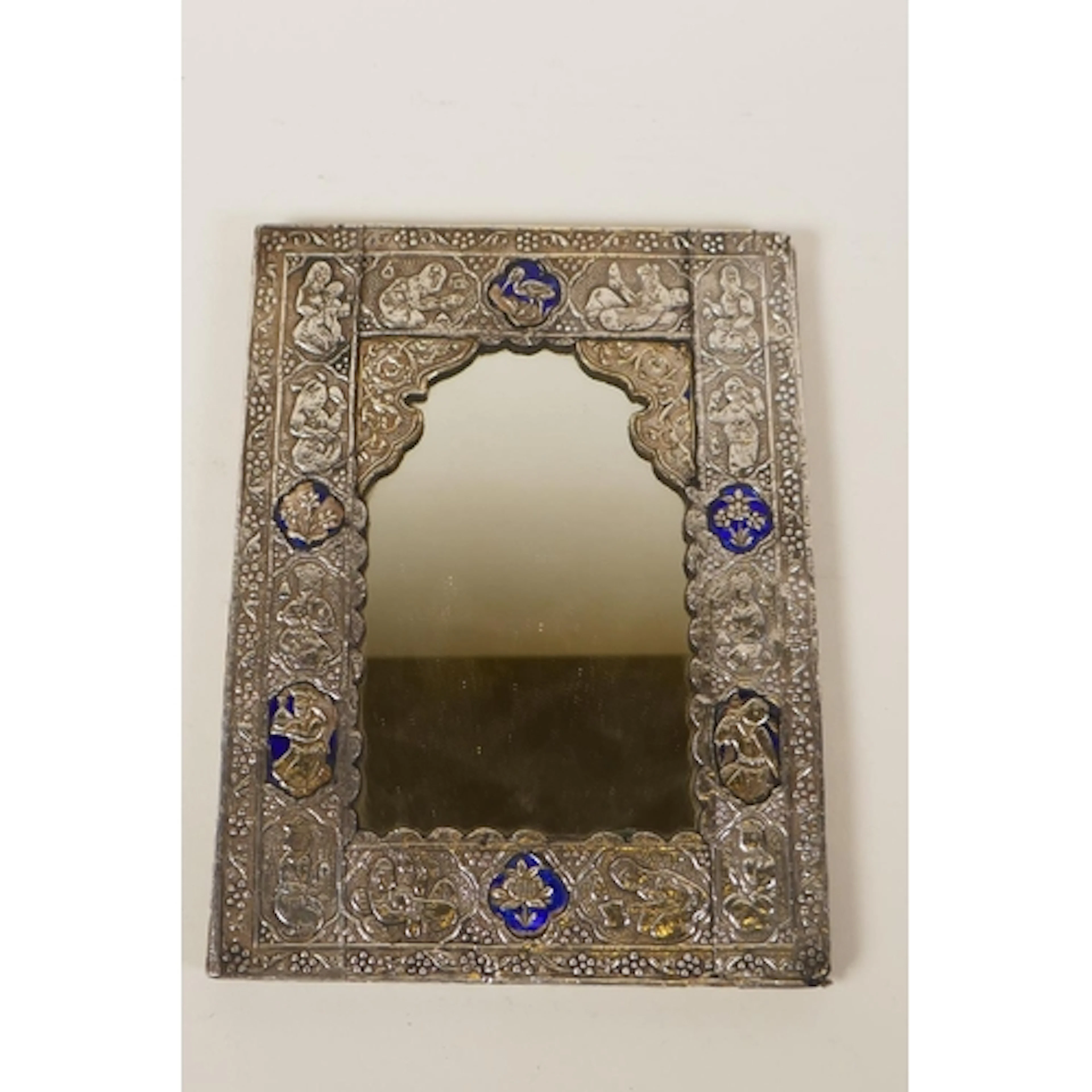 An Indo Persian white metal framed mirror with repousse figu...