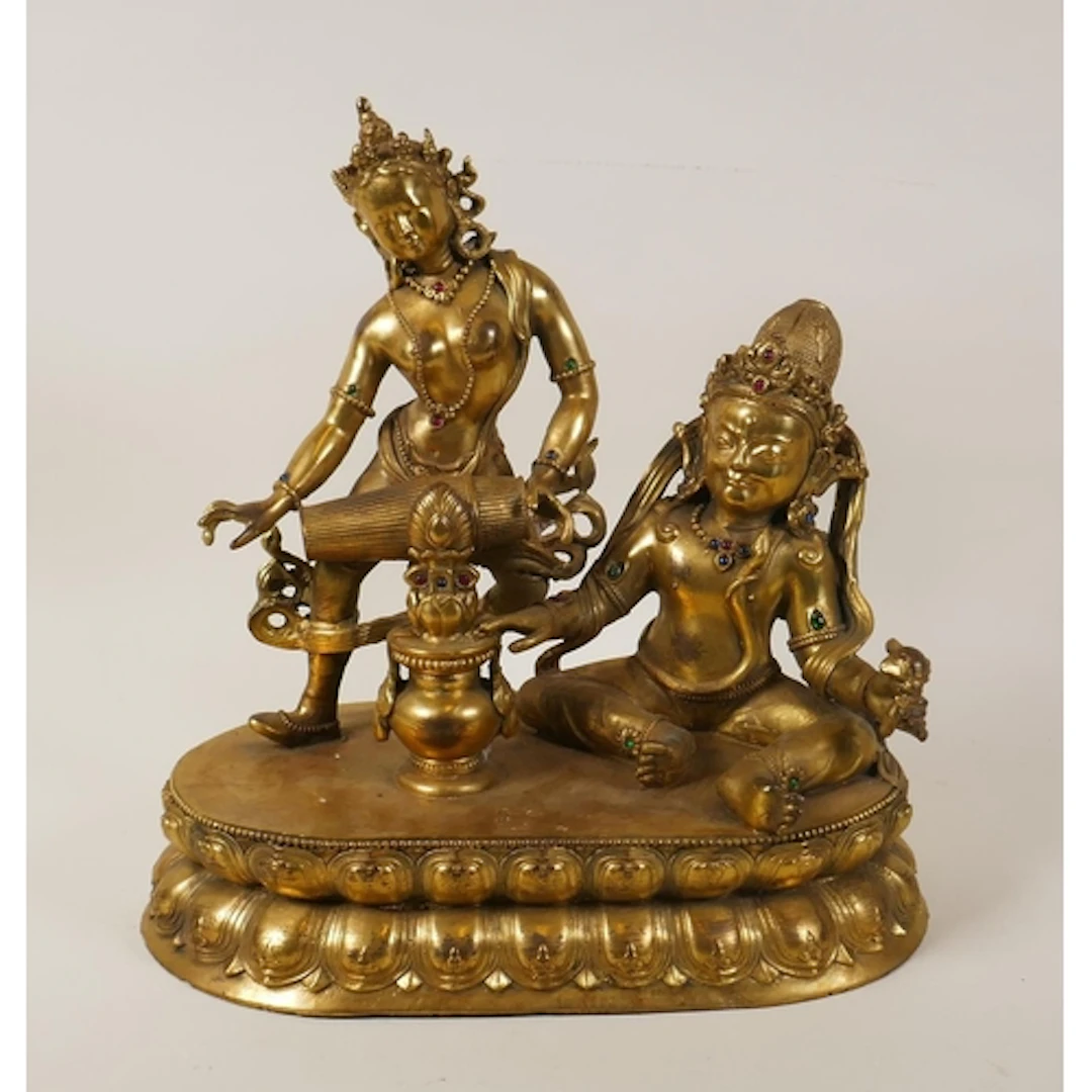 A Tibetan gilt bronze figure group of Jambhala and an apsara...