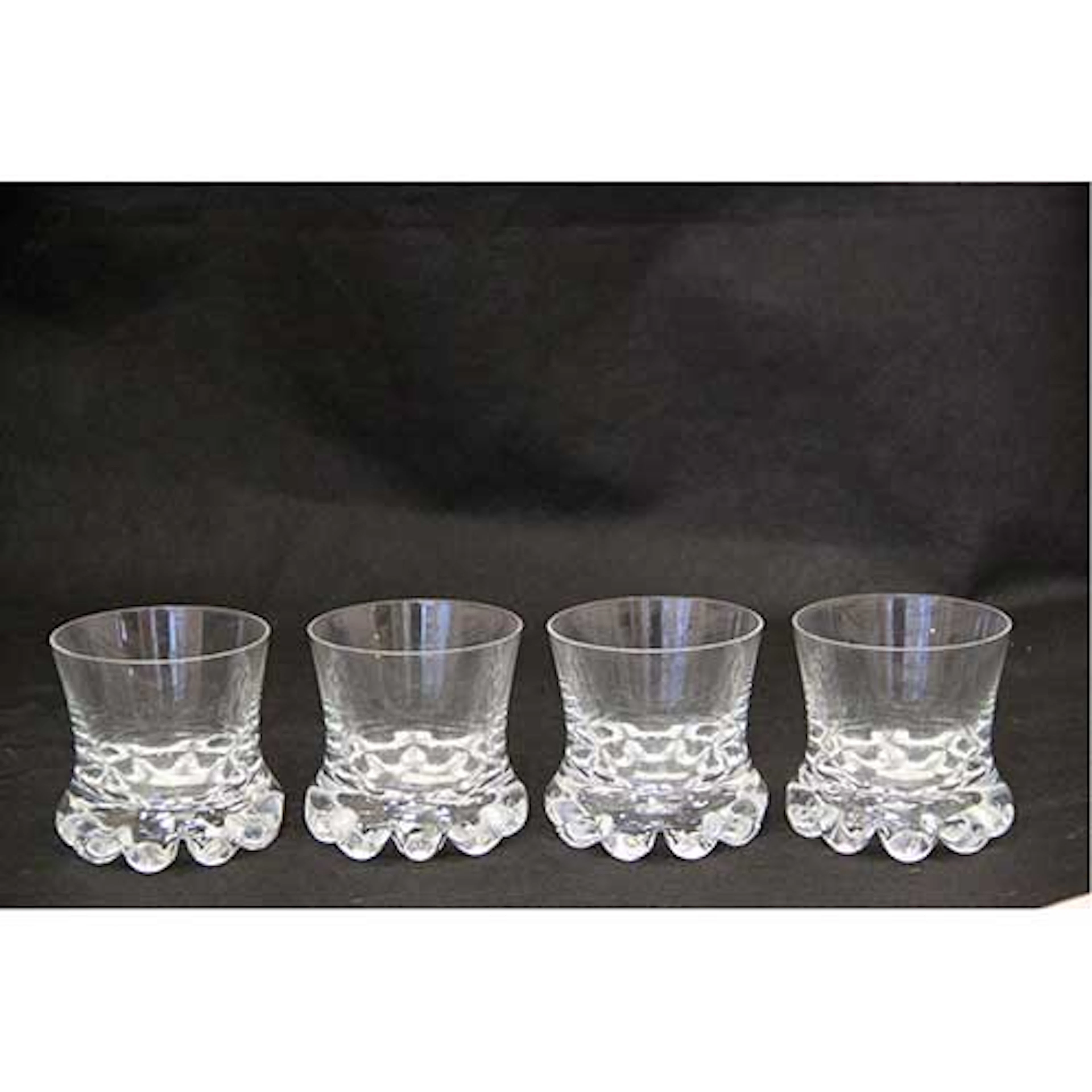 Lote de cuatro vasos bajos para licor en cristal con base alabeada.