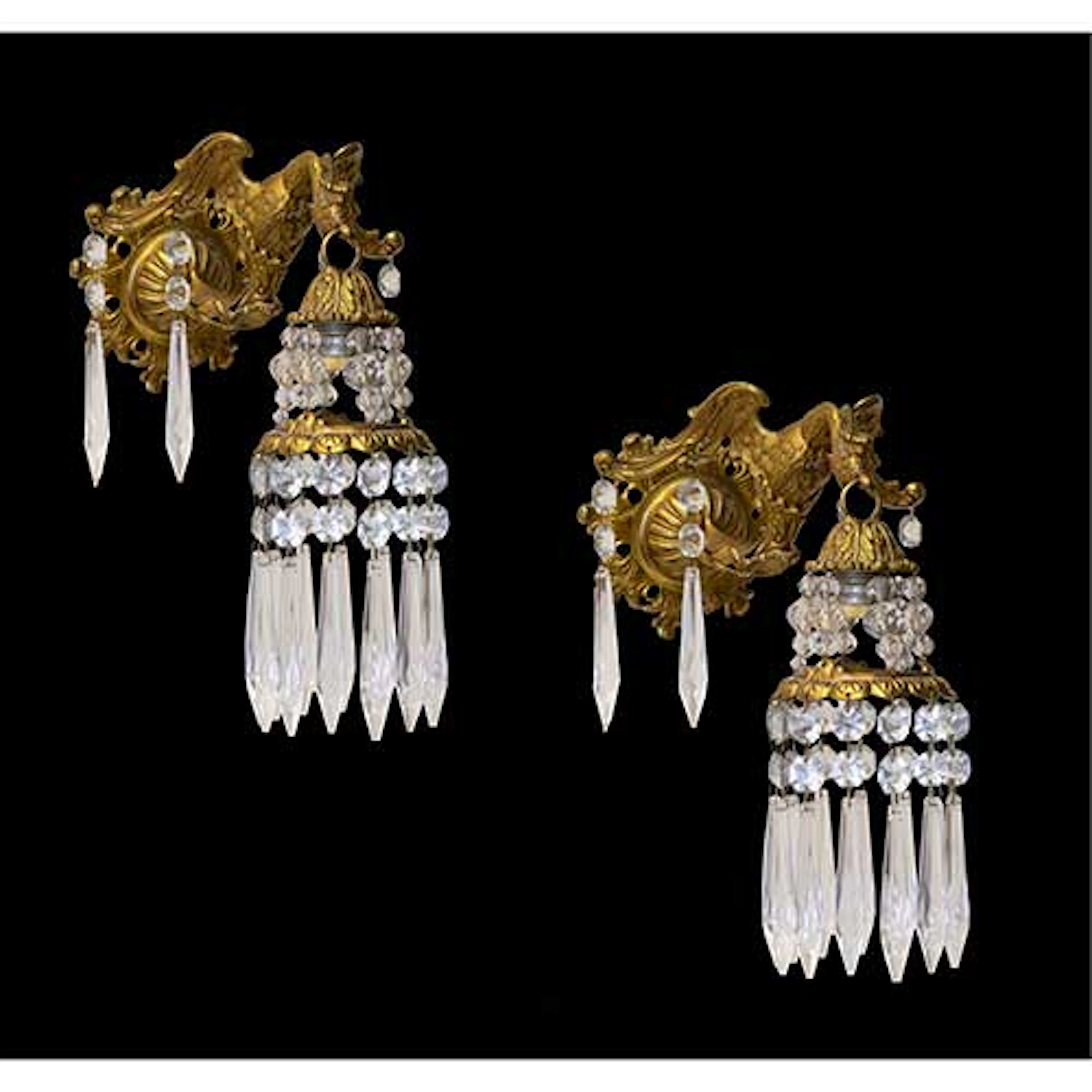 Pareja de apliques de pared en bronce dorado con forma de aves coronadas.