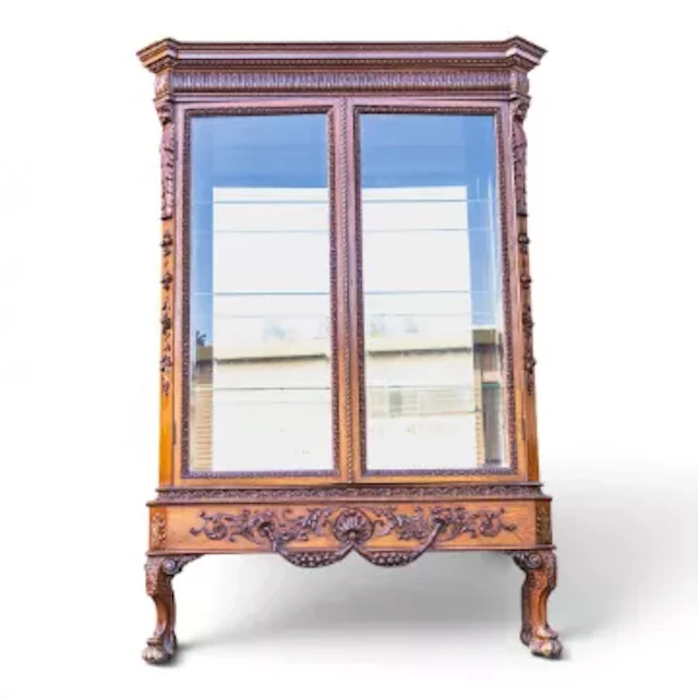 Carved wooden display cabinet featuring double glass doors and intricate