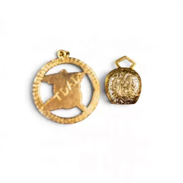 Yellow metal cow bell charm and circular pendant, both items electronically