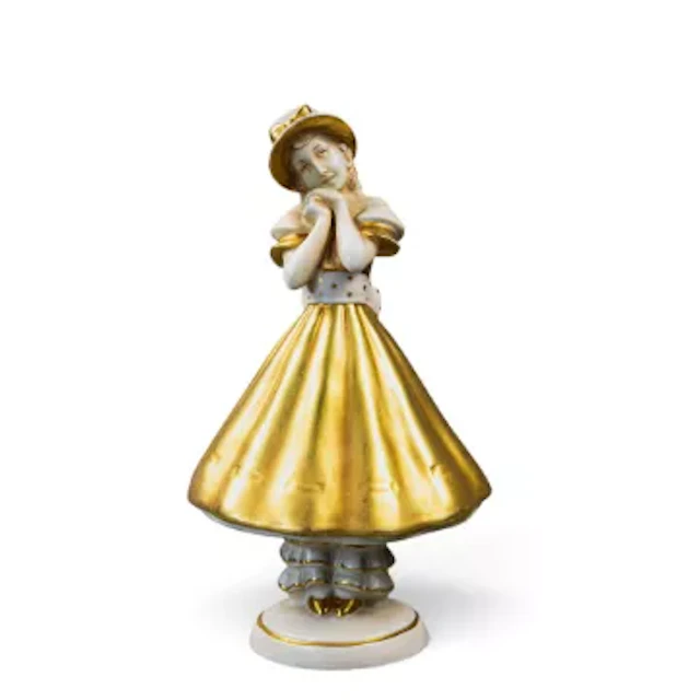 A Royal Dux figure of a woman in a flowing gold dress and bowed hat