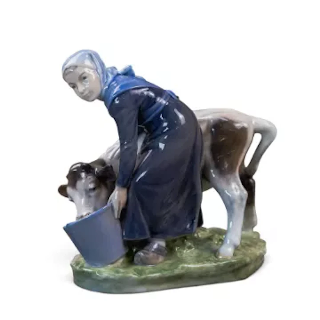 A Royal Copenhagen figure of a girl feeding a calf, model number 779