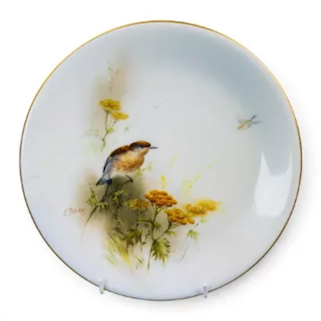 A Royal Worcester plate, decorated with a bird on a branch amongst