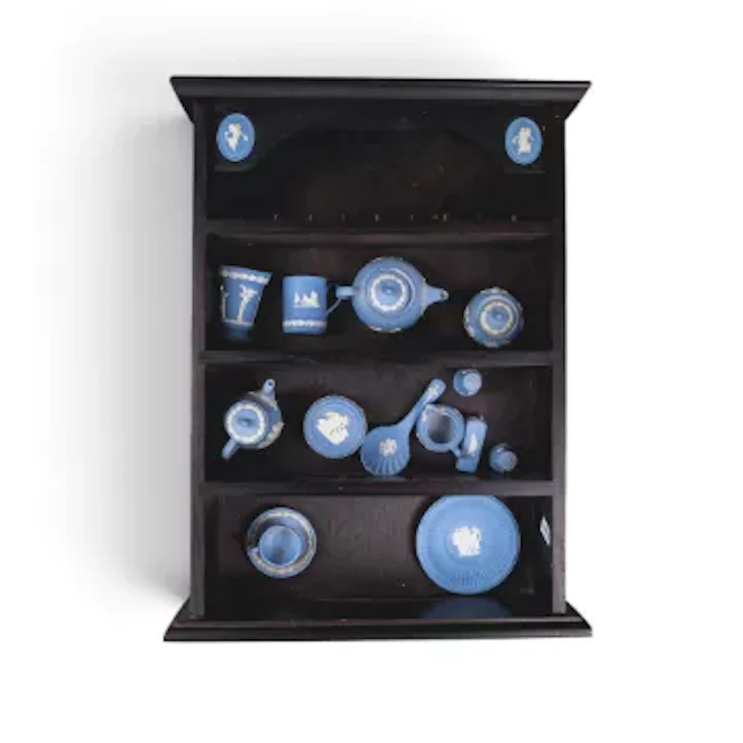 A collection of miniature Wedgwood Jasper pieces in a wooden display