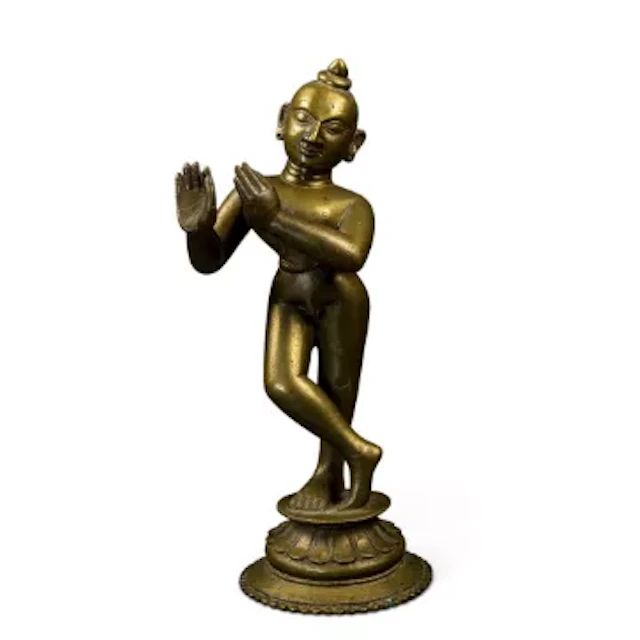 A cast brass statue of Lord Krishna on a pedestal base, height 23cm.