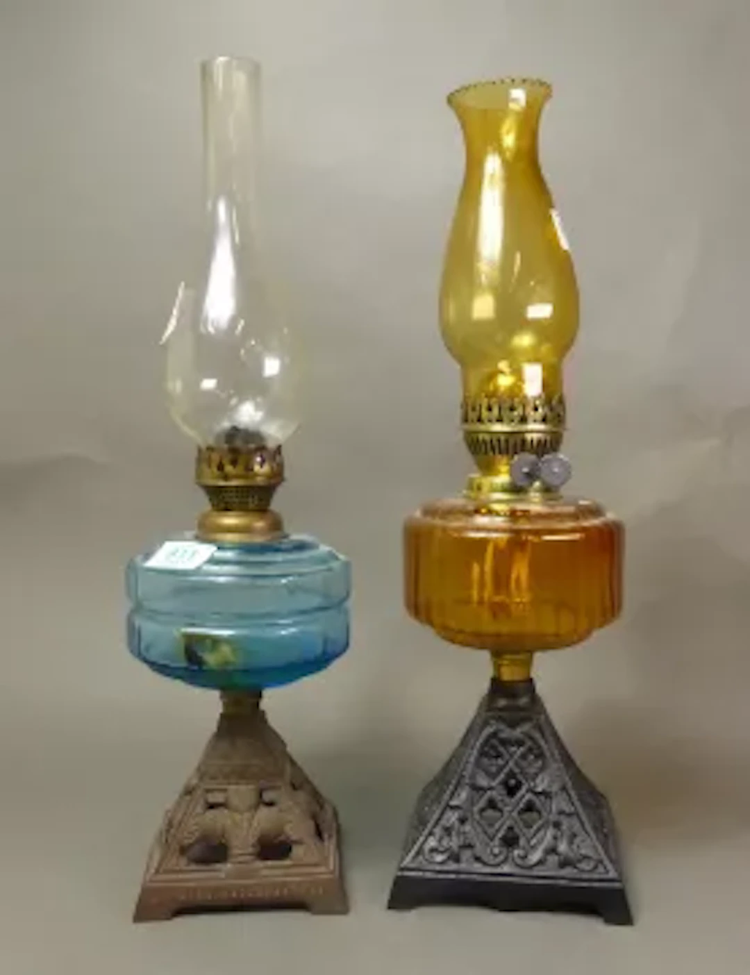 Two oil lamps, both on angular metal bases, one with a blue glass