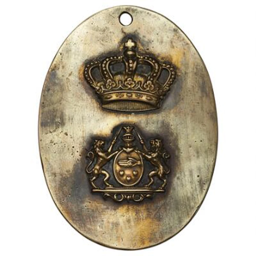 Oval brass police badge featuring a crown and a coat of arms with