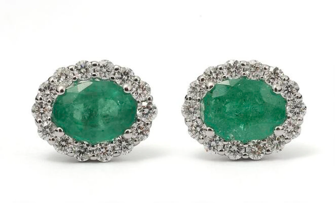 A pair of emerald and diamond ear studs each set with an emerald encircled